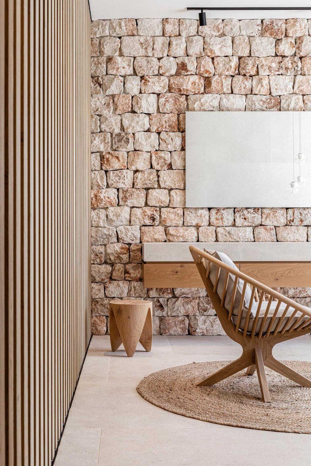 This Mallorca bathroom pairs textured stone walls with a floating vanity and a freestanding bathtub overlooking the sea.