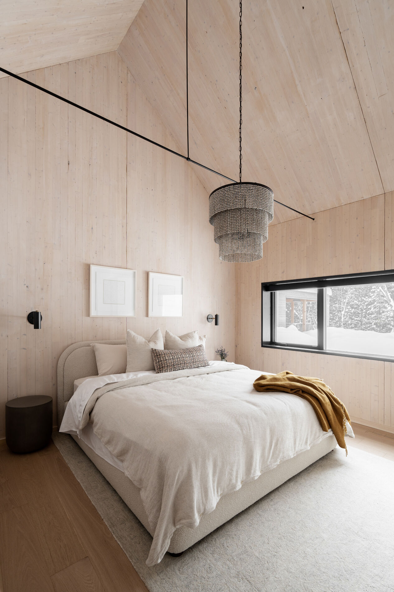 A modern mountain cabin inspired bedroom with wood walls and a built-in desk.
