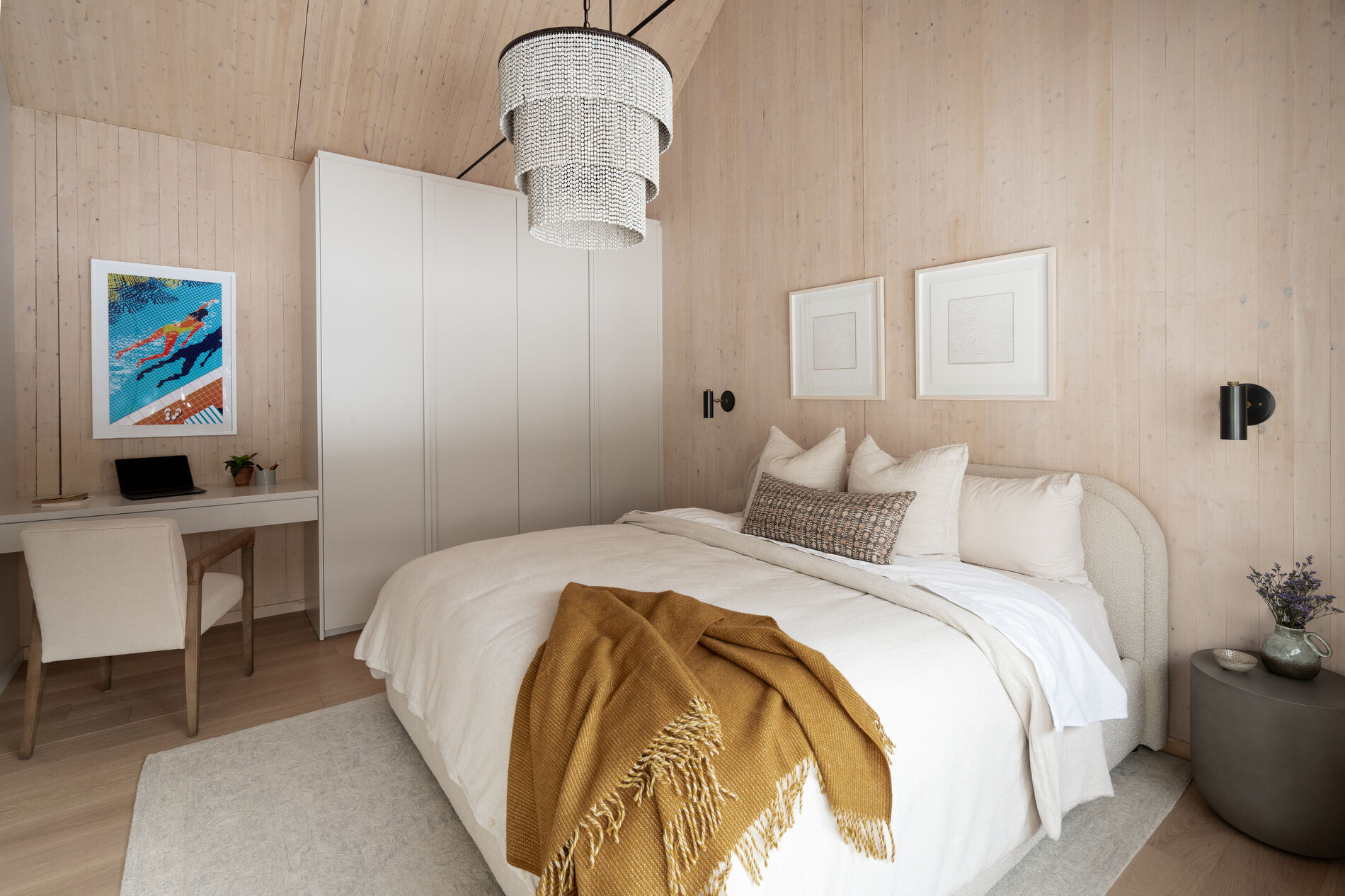 A modern mountain cabin inspired bedroom with wood walls and a built-in desk.