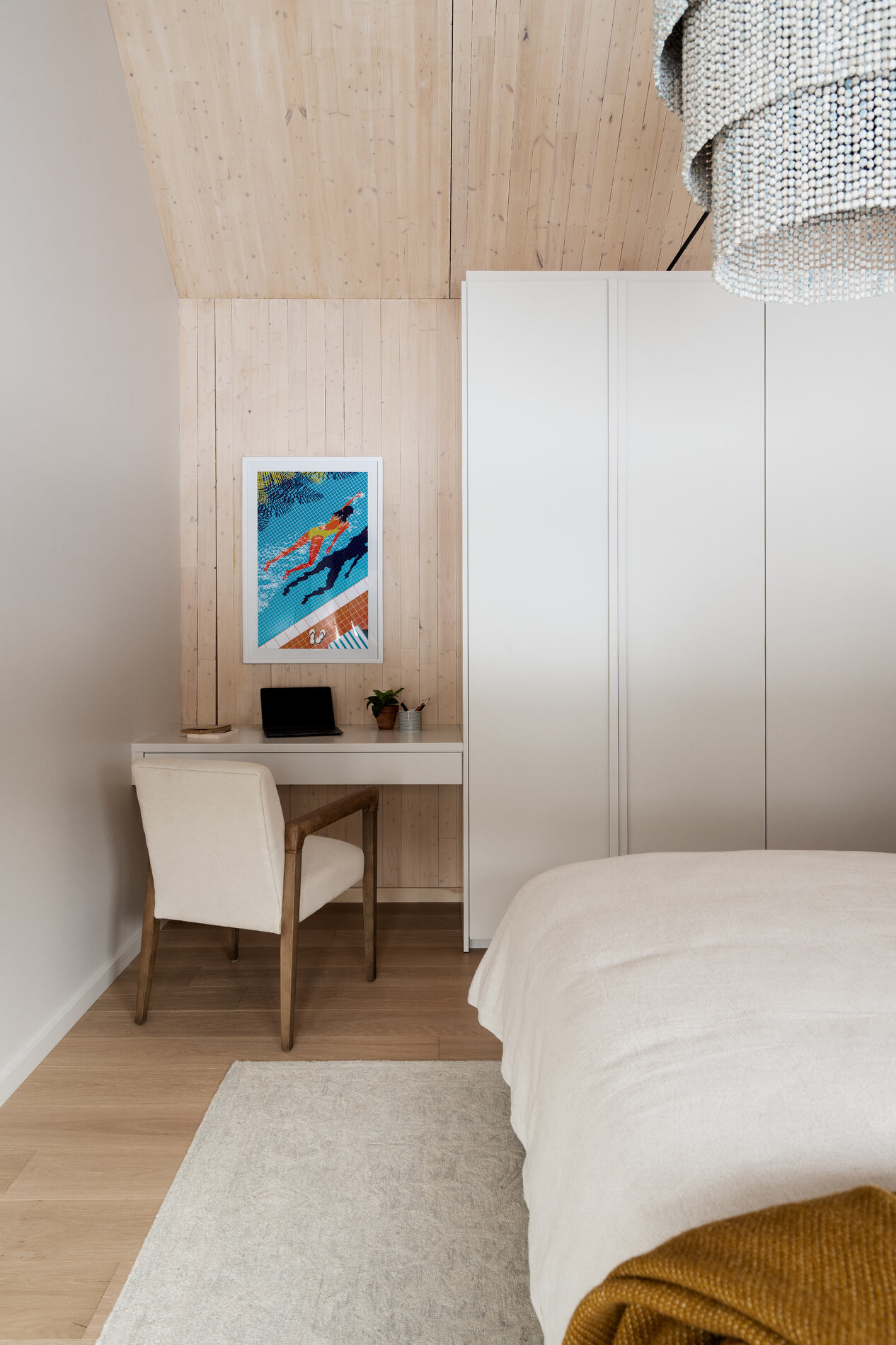 A modern mountain cabin inspired bedroom with wood walls and a built-in desk.