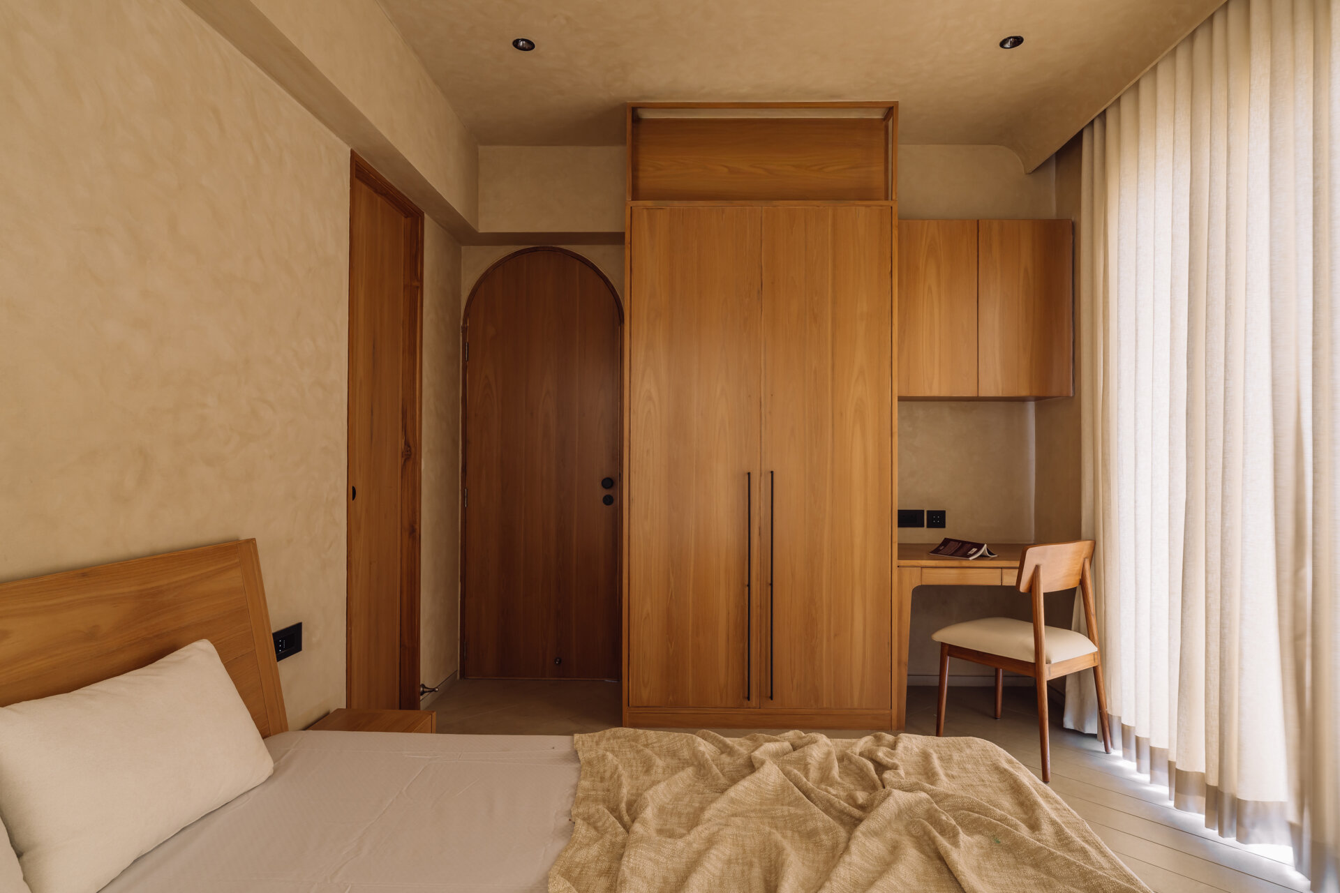Warm tones, smooth flooring, and integrated wooden details work together in this bedroom to create a simple and calming environment suited to rest and quiet activities.