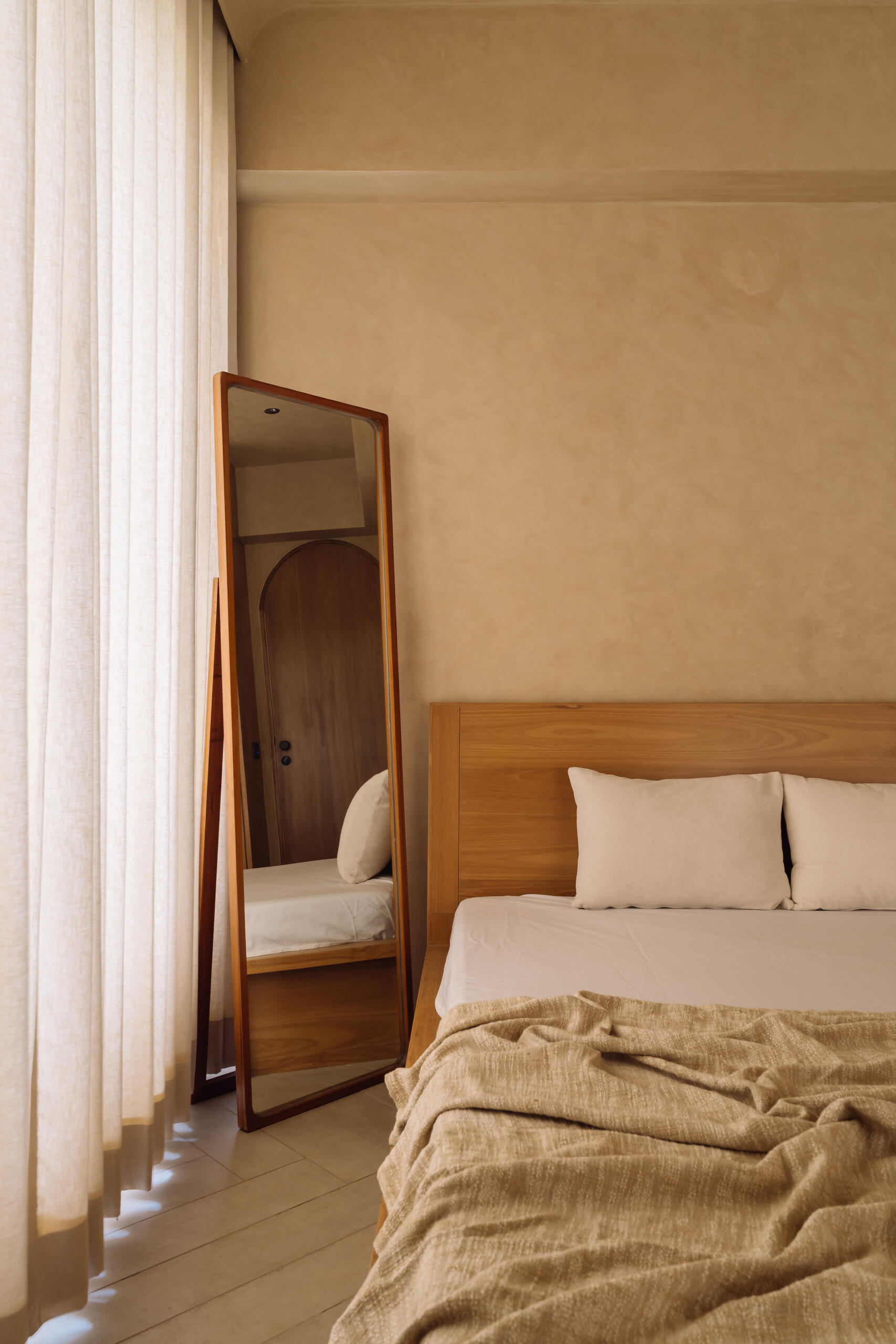 Warm tones, smooth flooring, and integrated wooden details work together in this bedroom to create a simple and calming environment suited to rest and quiet activities.