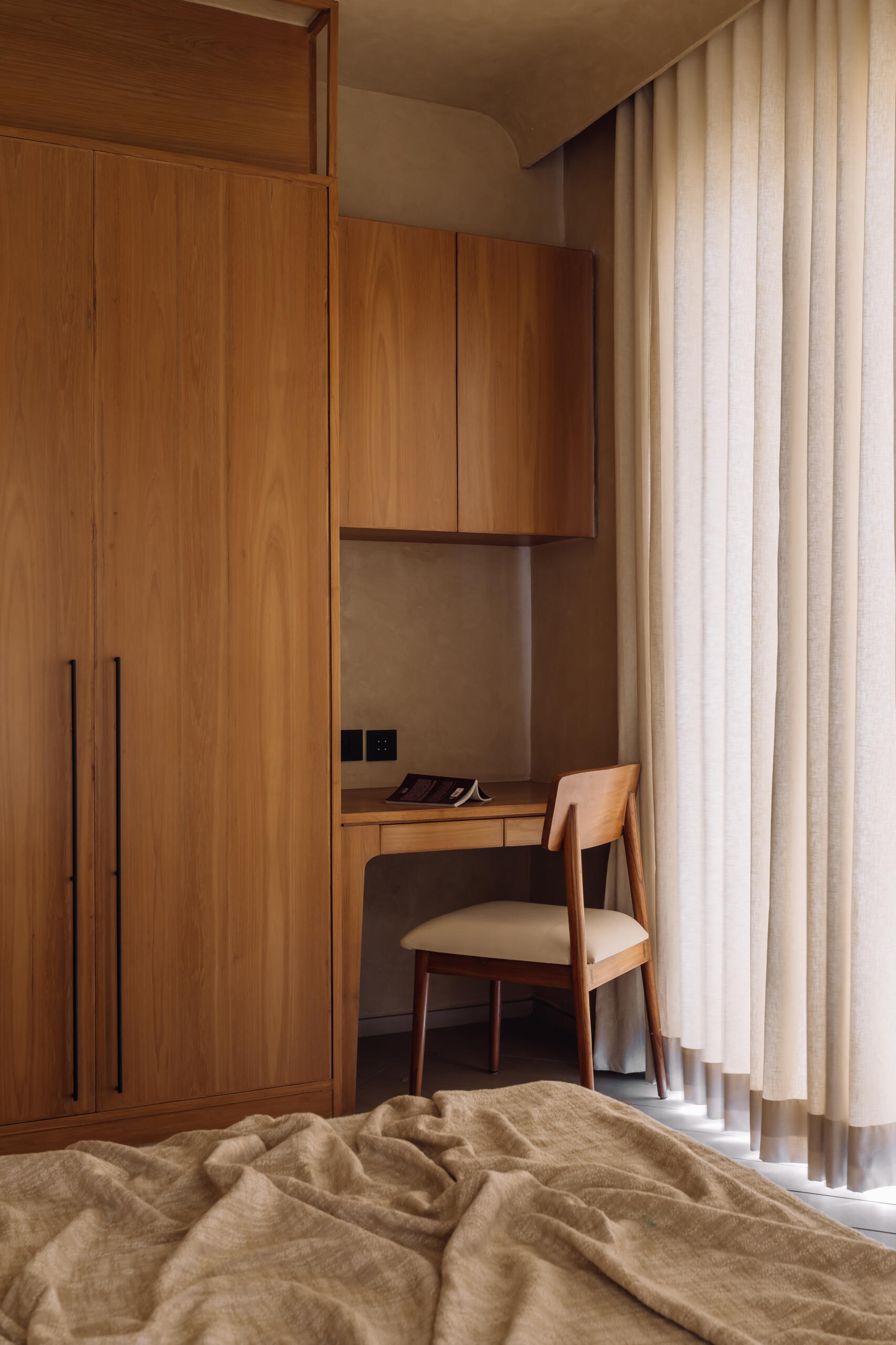 Warm tones, smooth flooring, and integrated wooden details work together in this bedroom to create a simple and calming environment suited to rest and quiet activities.