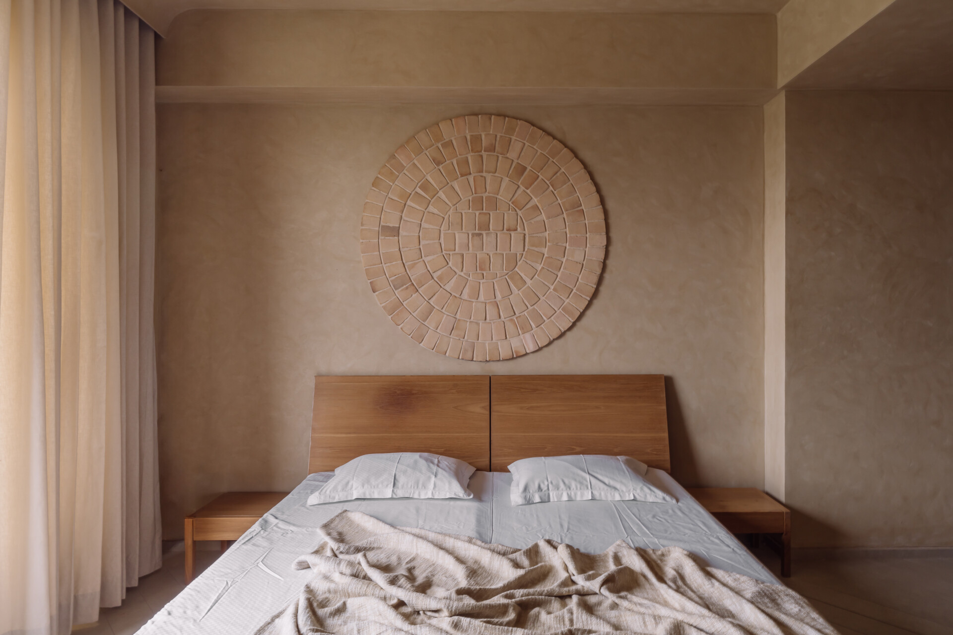 Warm tones, smooth flooring, and integrated wooden details work together in this bedroom to create a simple and calming environment suited to rest and quiet activities.