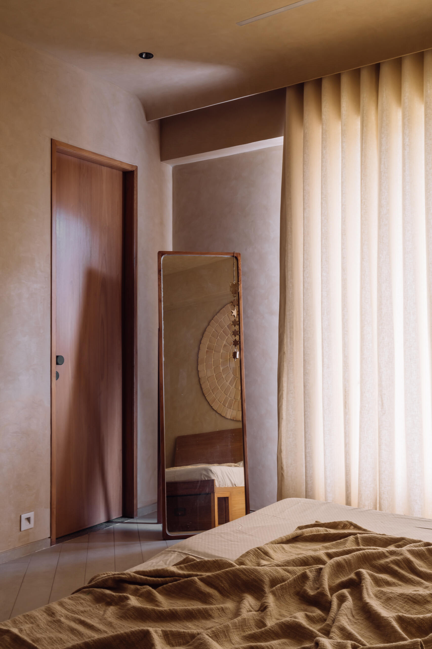 Warm tones, smooth flooring, and integrated wooden details work together in this bedroom to create a simple and calming environment suited to rest and quiet activities.