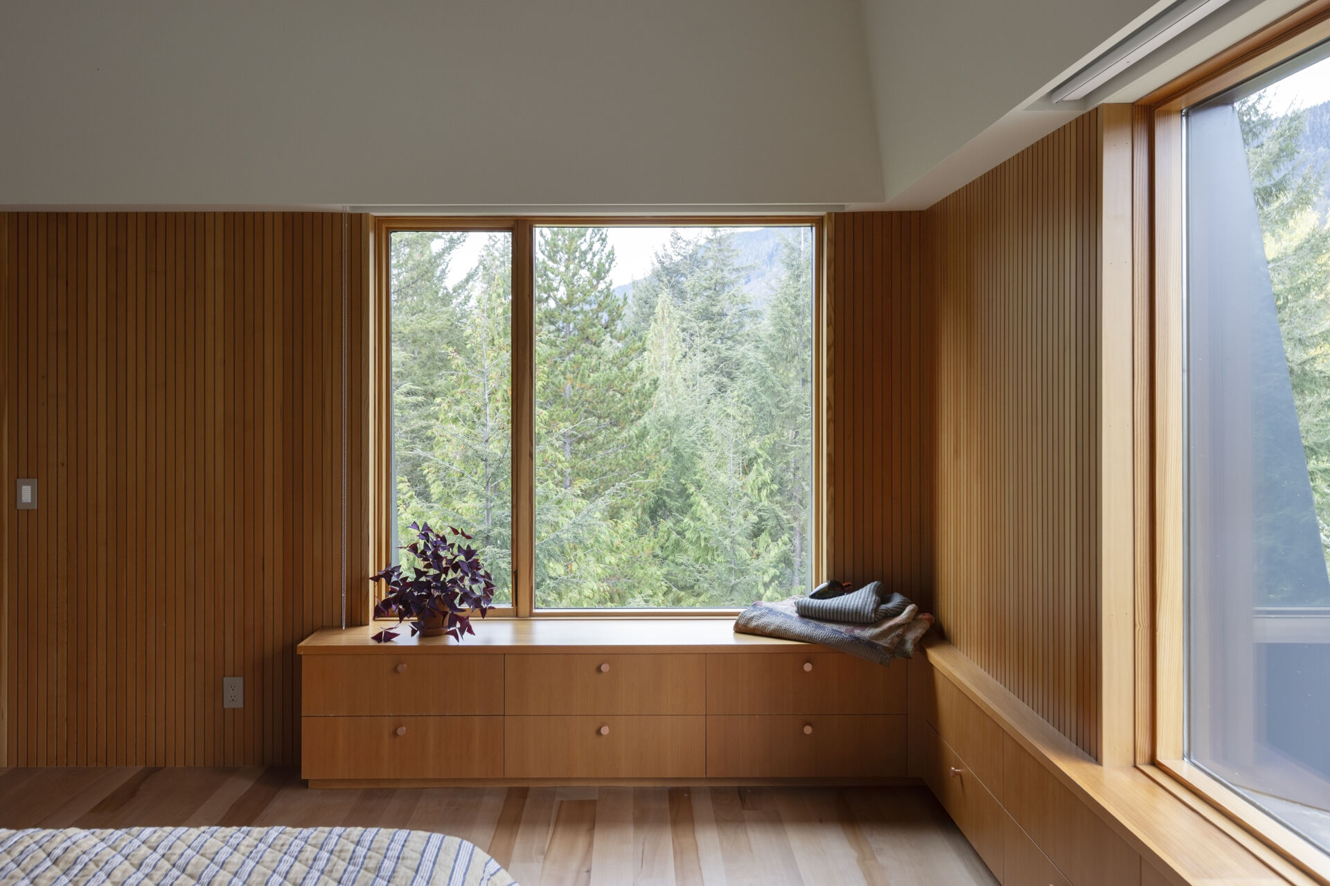 This treehouse-inspired bedroom features etched copper screens, forest views, and warm Pacific madrone wood tones.