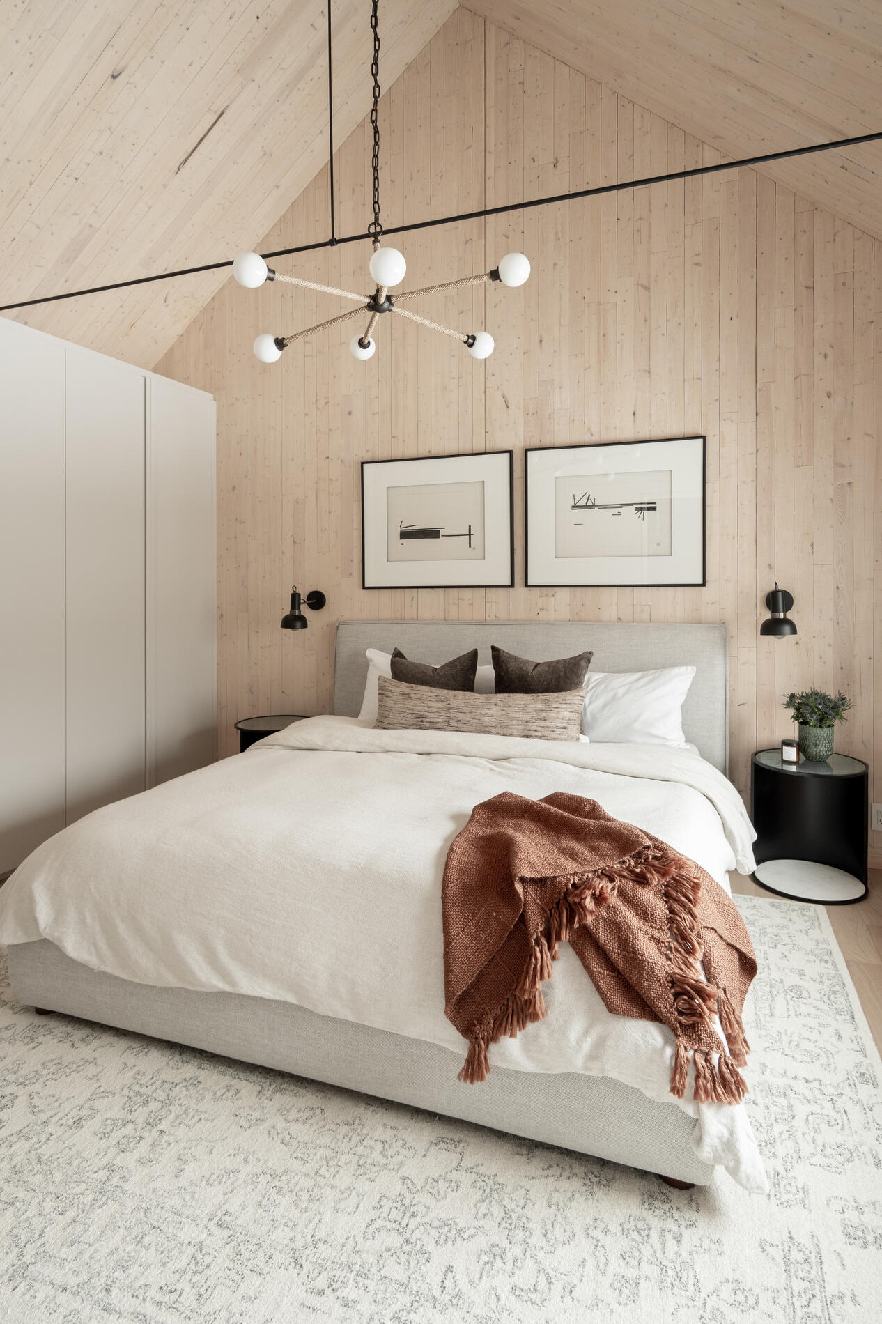 A modern mountain cabin inspired bedroom with wood walls and a built-in desk.