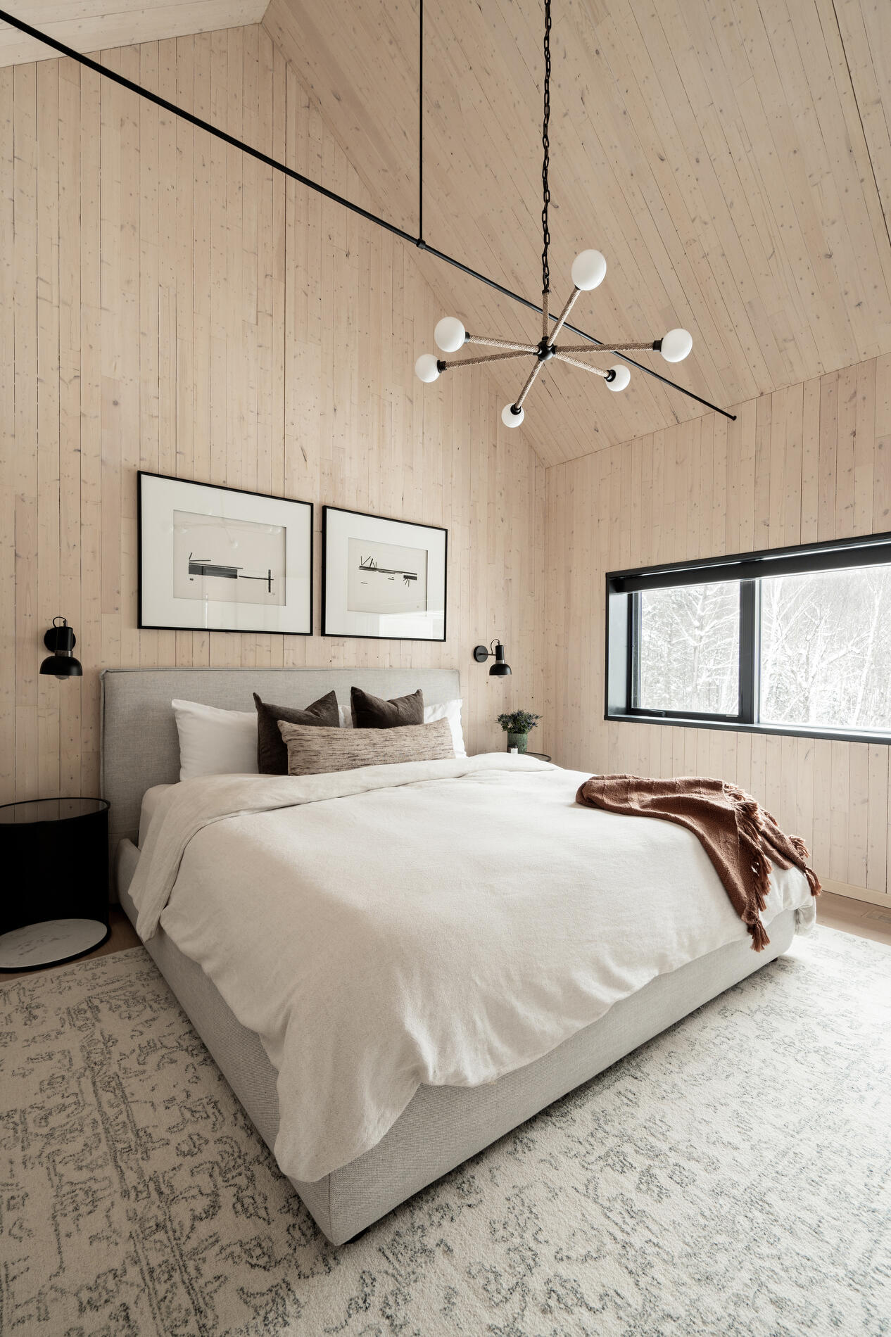 A modern mountain cabin inspired bedroom with wood walls and a built-in desk.