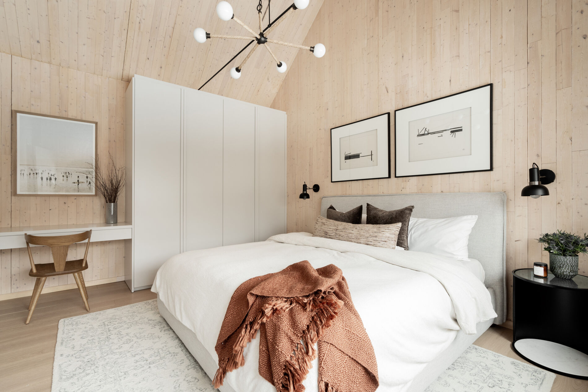 A modern mountain cabin inspired bedroom with wood walls and a built-in desk.