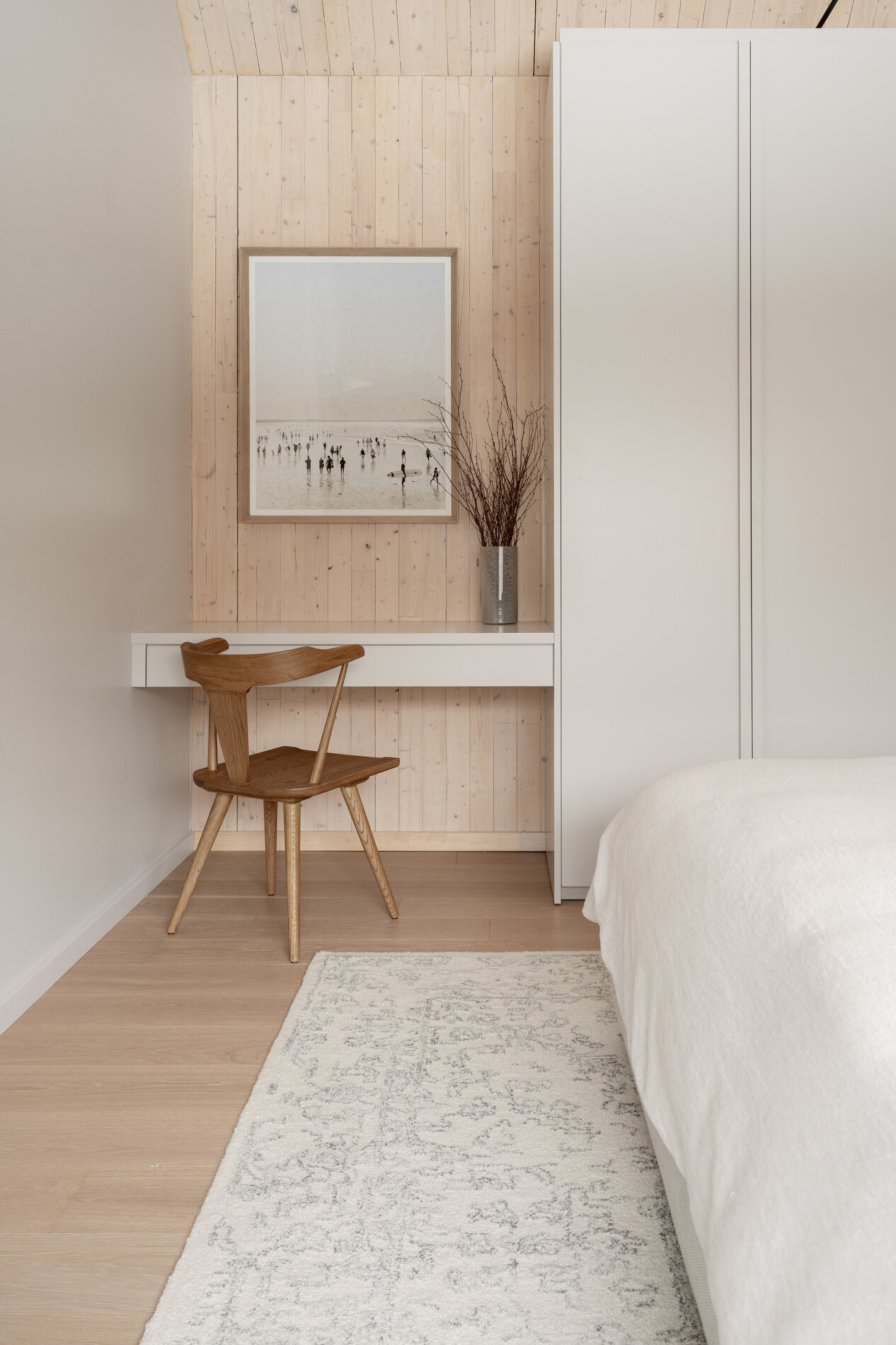 A modern mountain cabin inspired bedroom with wood walls and a built-in desk.