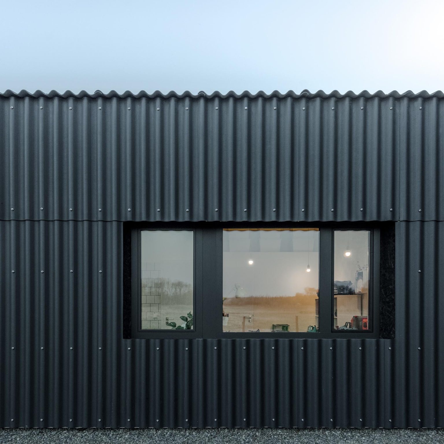 Black corrugated fiber-cement siding gives this Hungarian home its bold industrial look while creating a durable exterior that continues seamlessly across the roof.