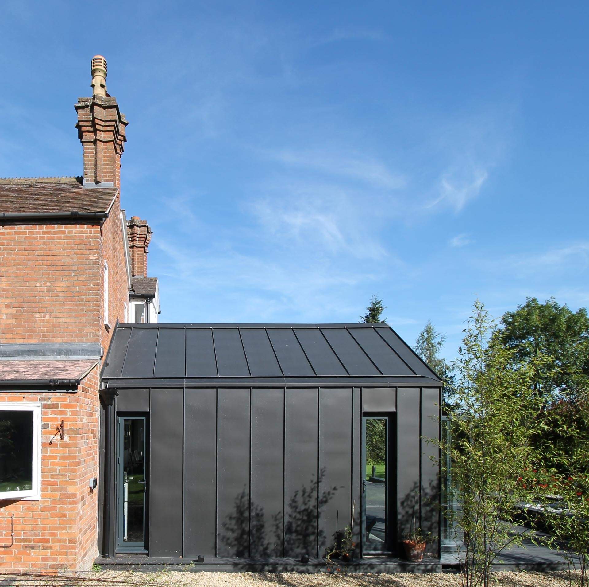 Black zinc cladding and dramatic pitched roofs give this Wiltshire extension a bold architectural look while still connecting beautifully to the original Victorian home.