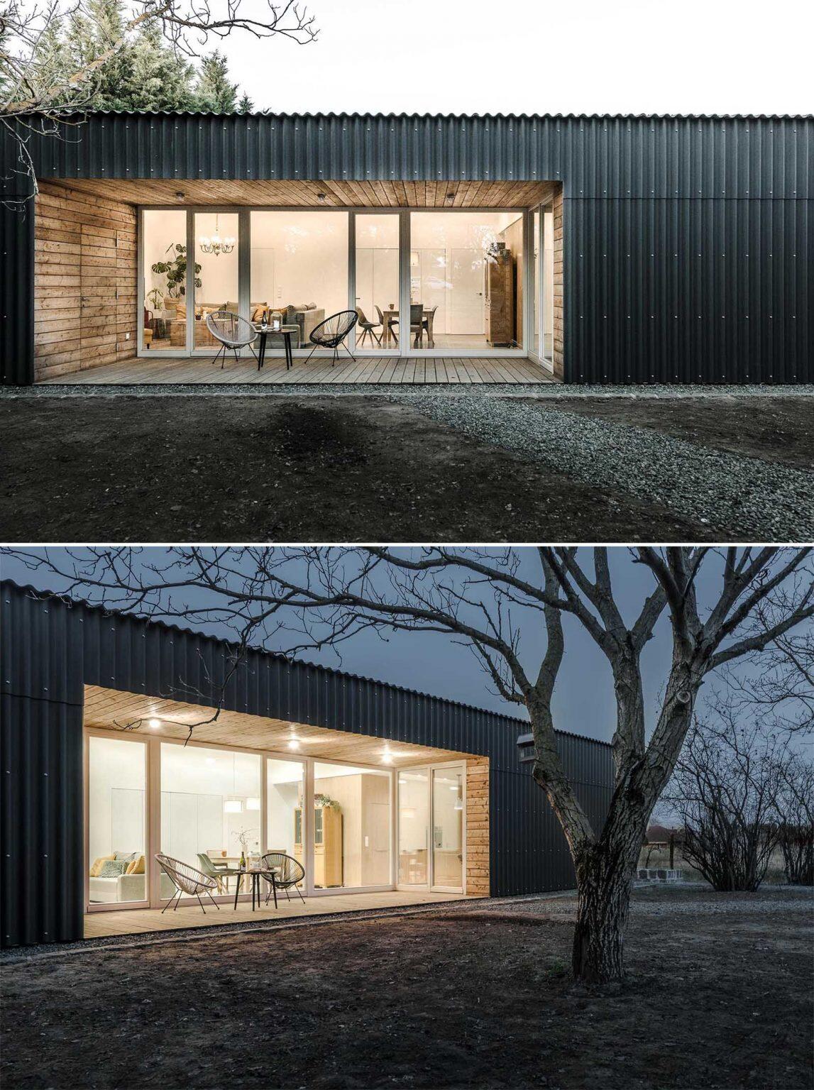 Larch wood-lined alcoves add warmth to this black modern home, creating inviting outdoor spaces that open directly toward the walnut grove.