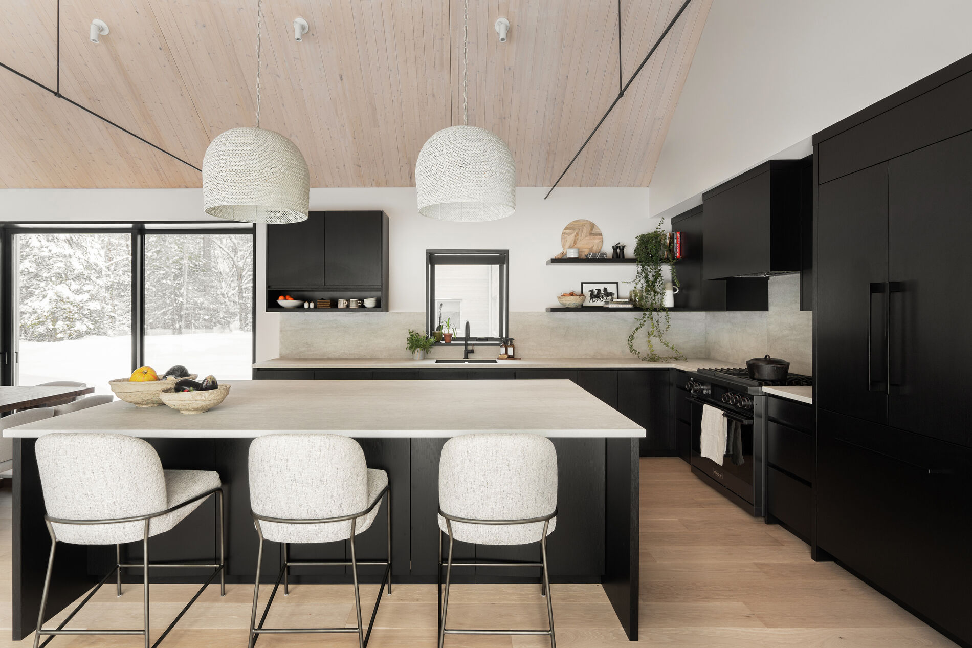 The kitchen features a restrained material palette with black cabinets providing contrast to the room. Positioned within easy reach of the dining area, it supports both everyday use and larger gatherings. 