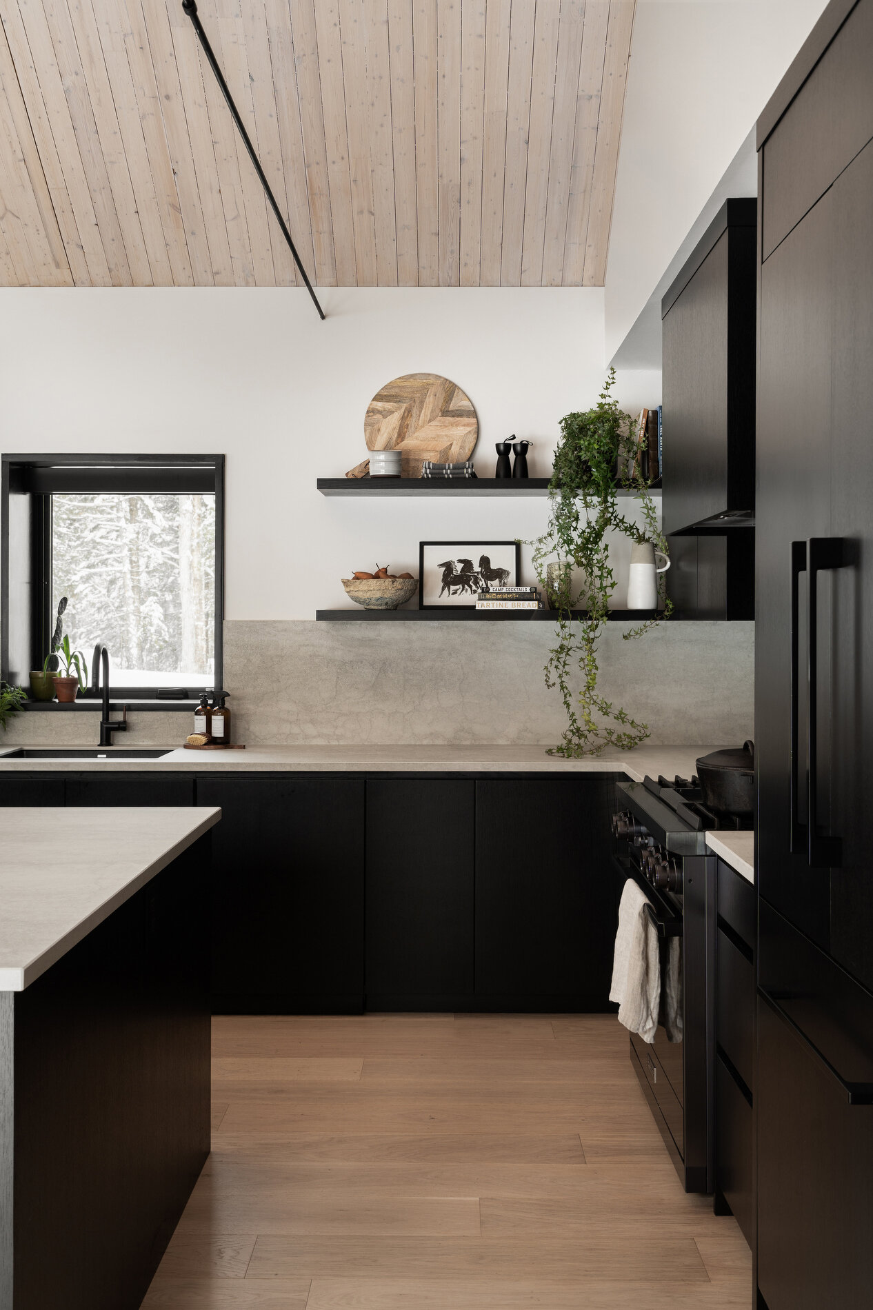 The kitchen features a restrained material palette with black cabinets providing contrast to the room. Positioned within easy reach of the dining area, it supports both everyday use and larger gatherings. 