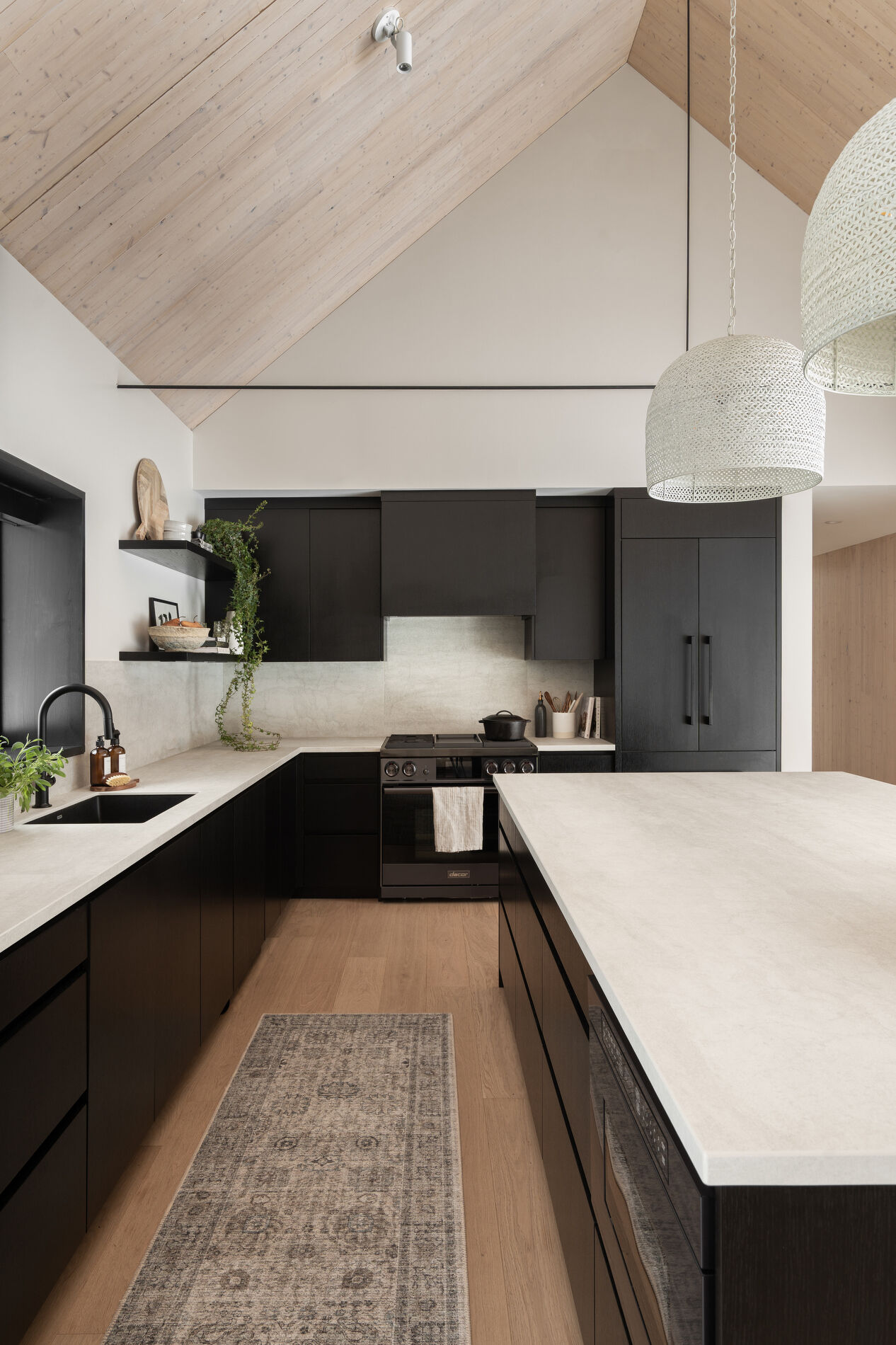 The kitchen features a restrained material palette with black cabinets providing contrast to the room. Positioned within easy reach of the dining area, it supports both everyday use and larger gatherings. 