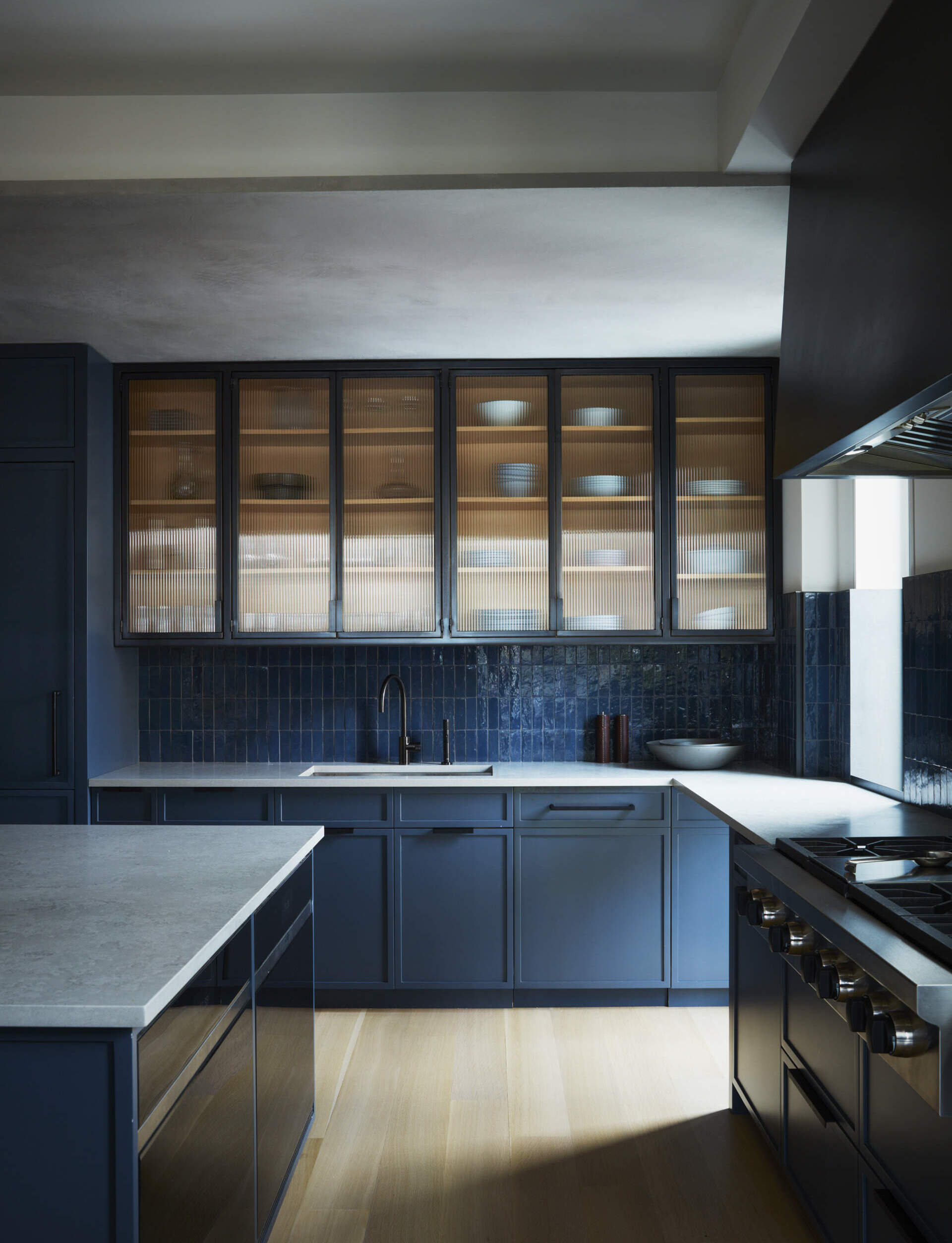 This navy kitchen pairs White Oak, blackened steel, quartz countertops, and Zellige tiles for a bold modern look.
