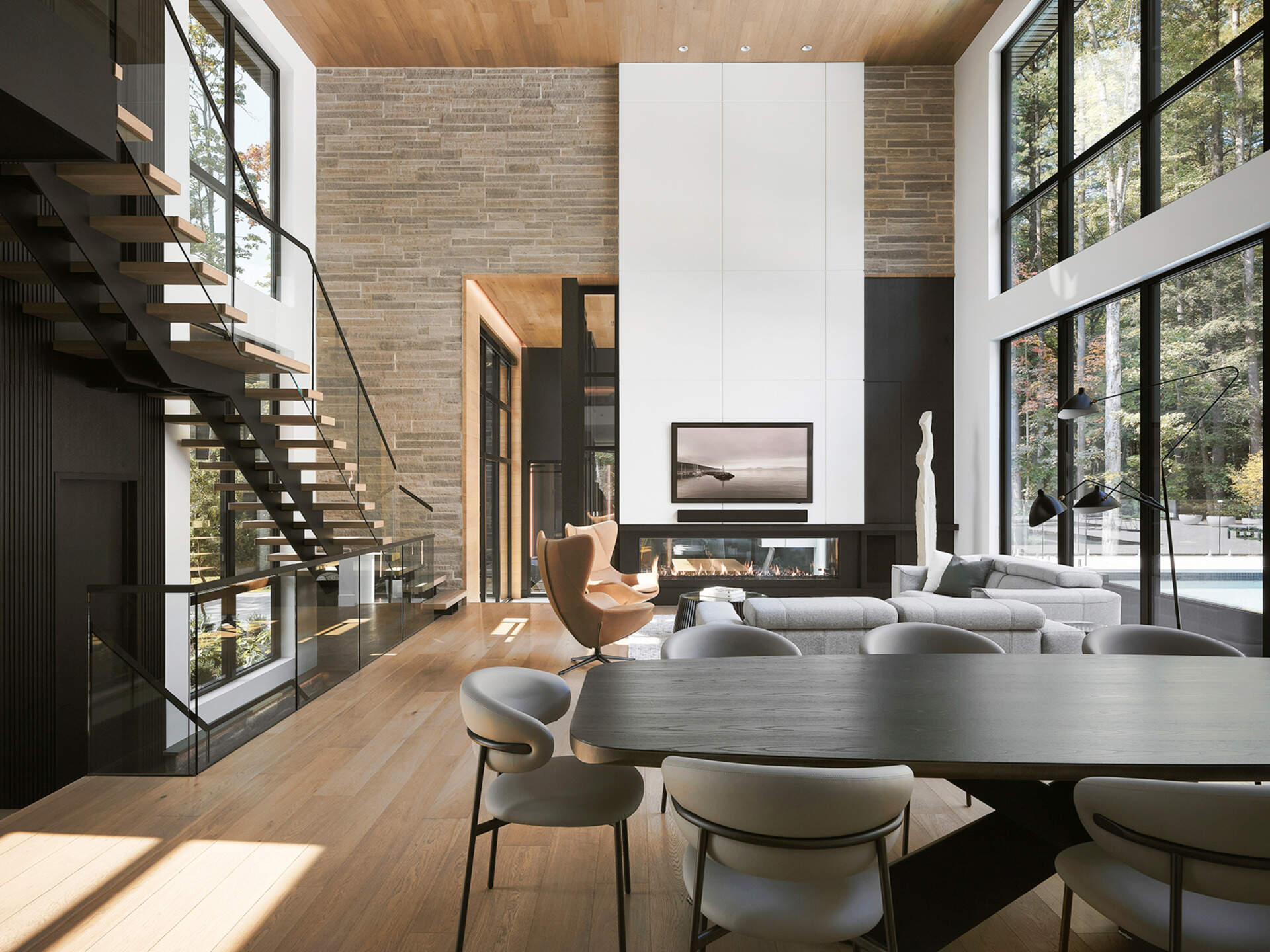 A modern living room with a double-height wood-lined ceiling, fireplace, and open floor plan.