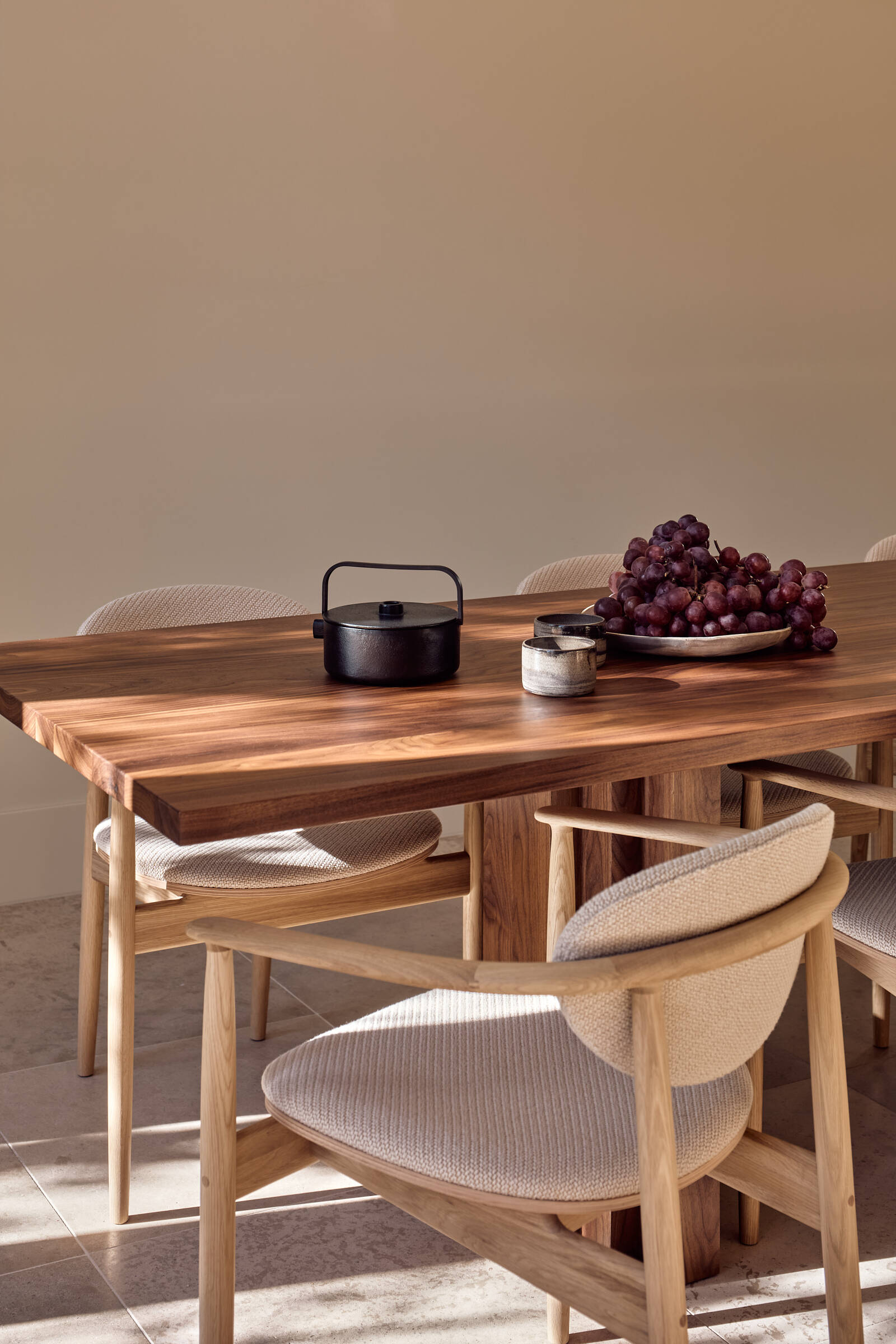 This elegant dining space pairs a dark walnut table with soft neutral interiors and open views toward the kitchen and garden.
