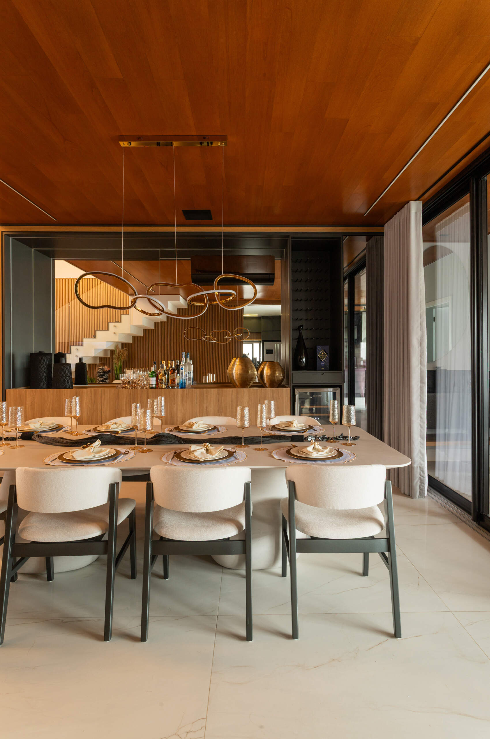 This modern dining room in Casa R|L features open-plan living, warm finishes, and seamless flow between interior spaces in a contemporary home in Brazil.