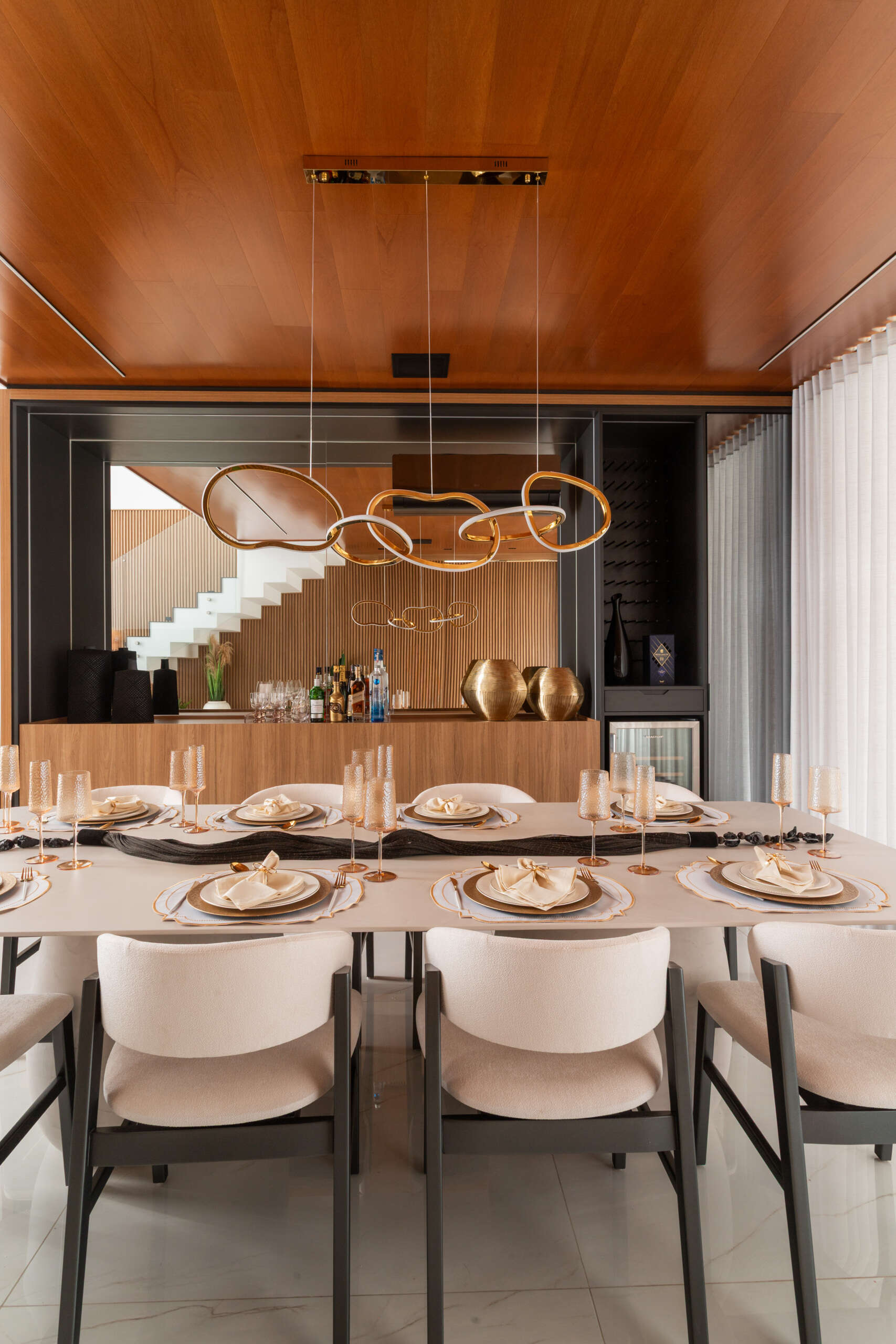 This modern dining room in Casa R|L features open-plan living, warm finishes, and seamless flow between interior spaces in a contemporary home in Brazil.