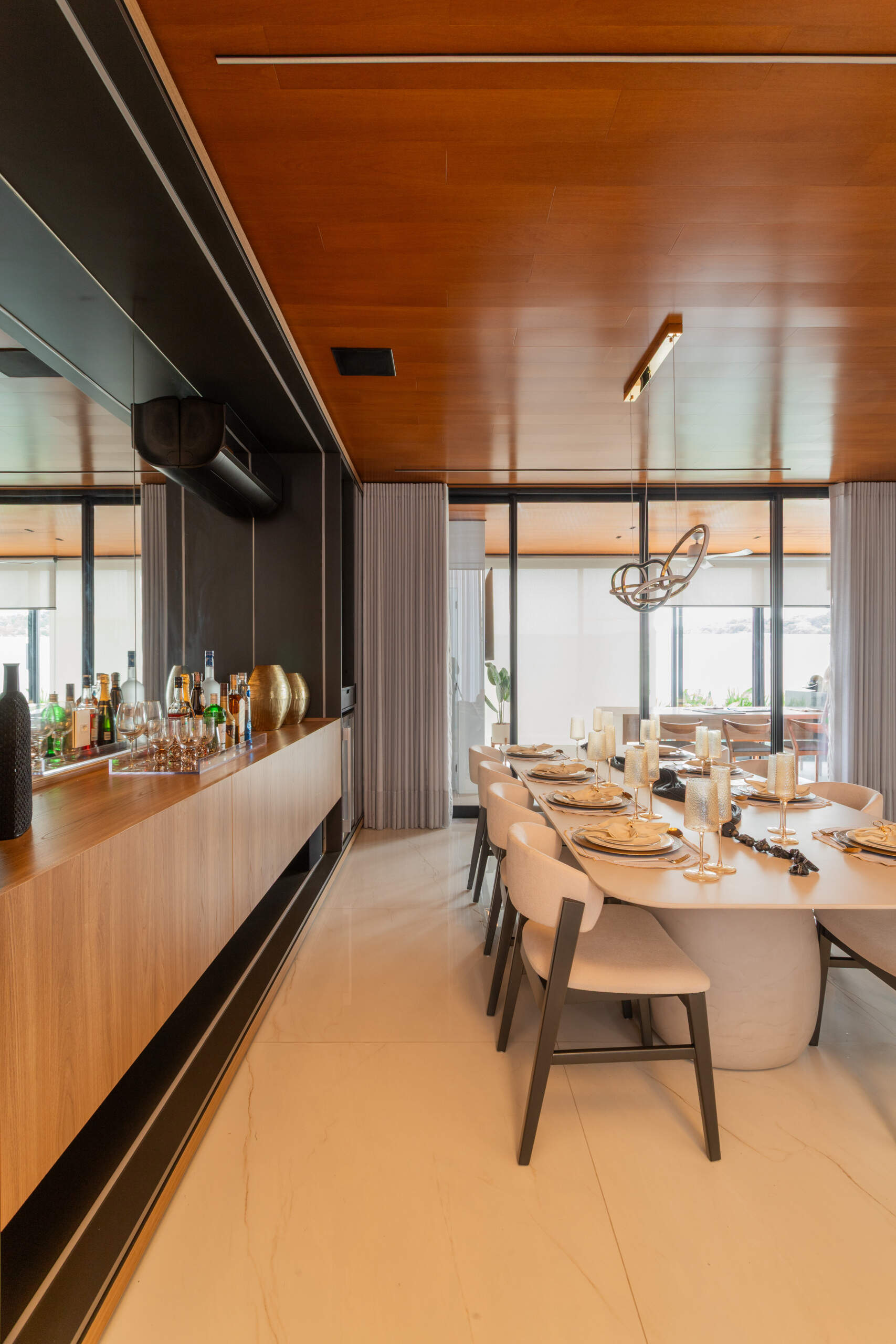 This modern dining room in Casa R|L features open-plan living, warm finishes, and seamless flow between interior spaces in a contemporary home in Brazil.