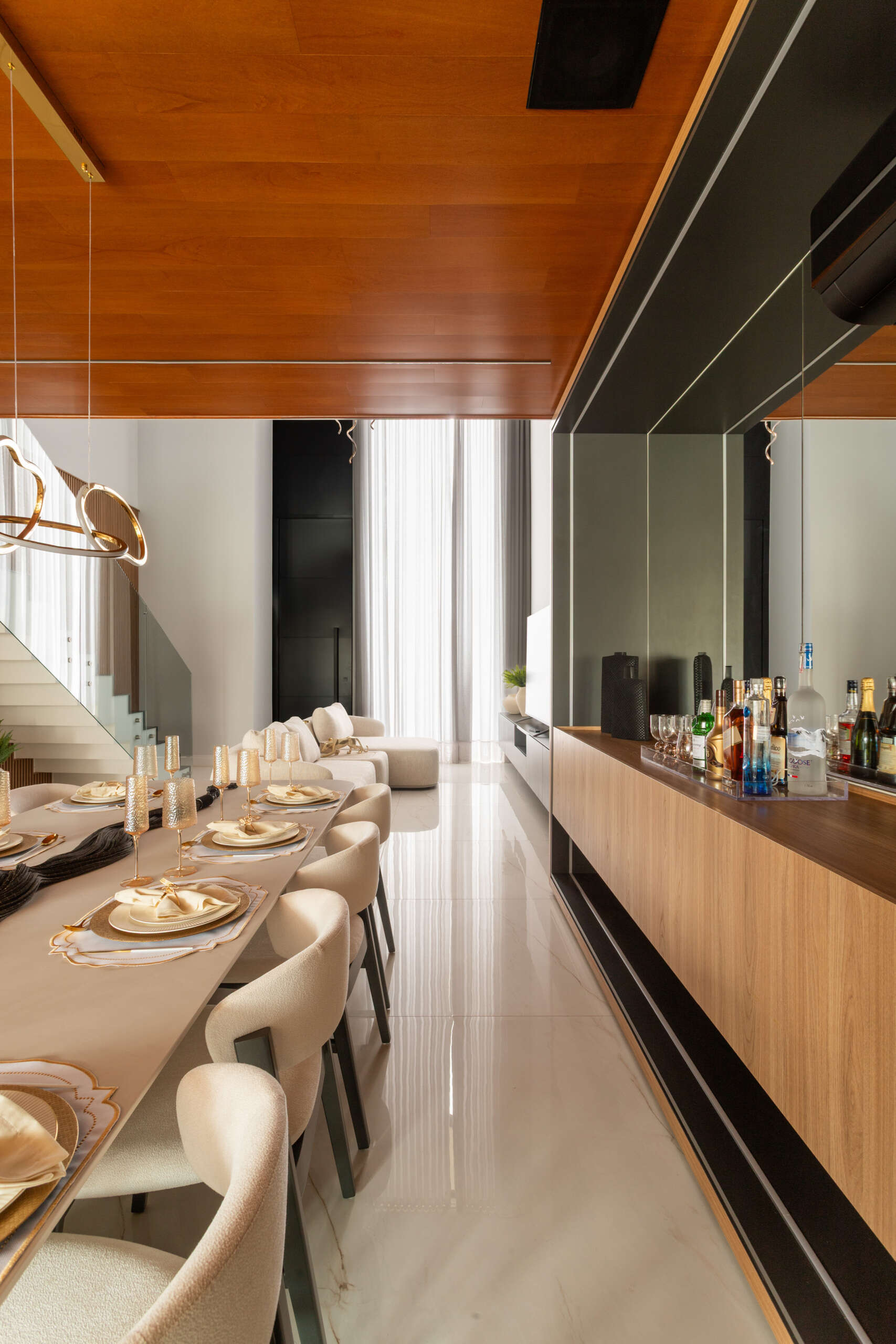 This modern dining room in Casa R|L features open-plan living, warm finishes, and seamless flow between interior spaces in a contemporary home in Brazil.
