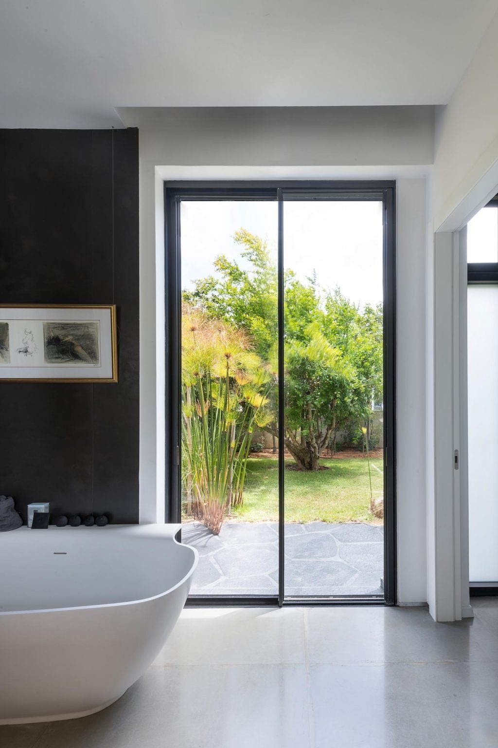 Freestanding bathtubs, black accents, floating wood vanities, and LED mirrors define these modern bathroom interiors.