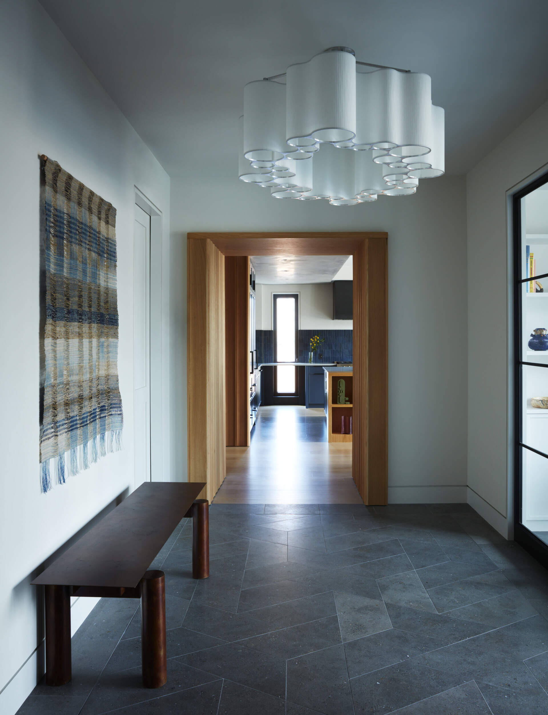 Custom limestone flooring, sculptural lighting, and woven textures create a sophisticated foyer inside this New York loft.