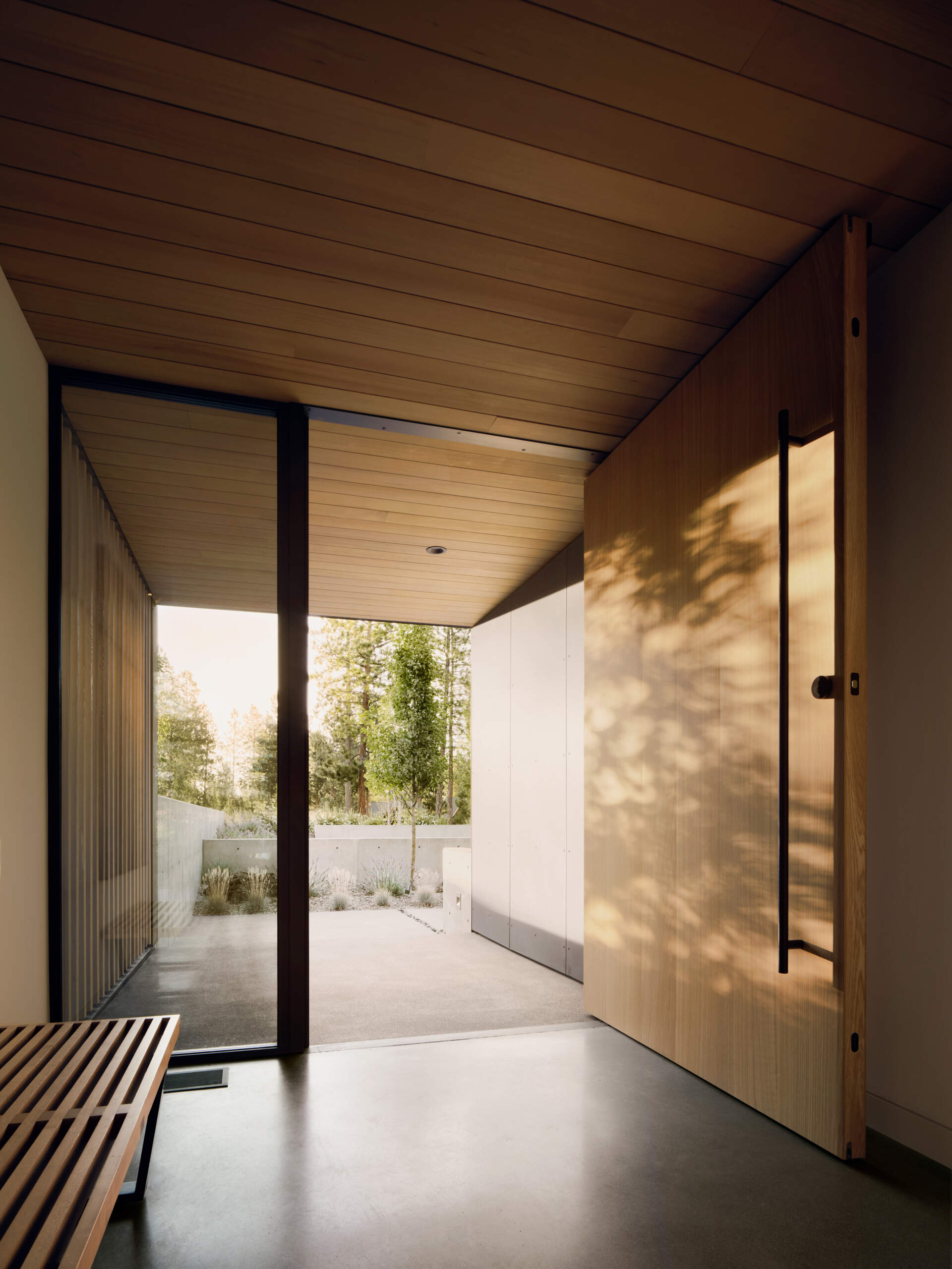 Glass walls, warm timber screens, and crisp modern lines create a stunning entrance experience at this contemporary Oregon home.