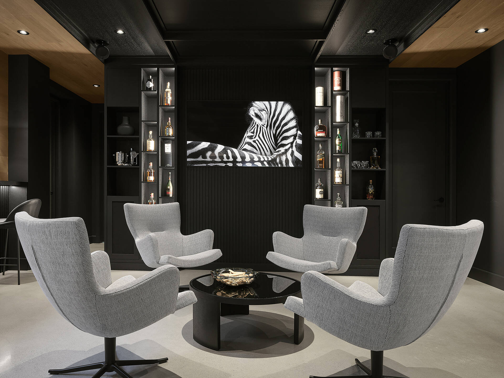 On the lower level, the games room, with its lounge area, pool table, kitchenette, and storage, benefits from the natural slope of the terrain, with a line of windows helping the space to feel bright and visually open despite being partially below grade. 