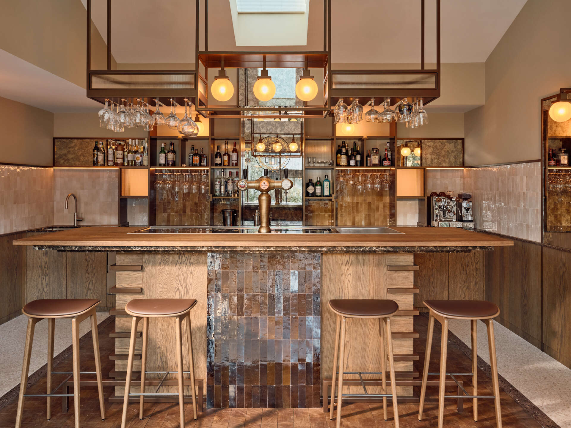 Terrazzo, brass shelving, zellige tiles, and warm brown tones give this private home bar an unforgettable atmosphere.