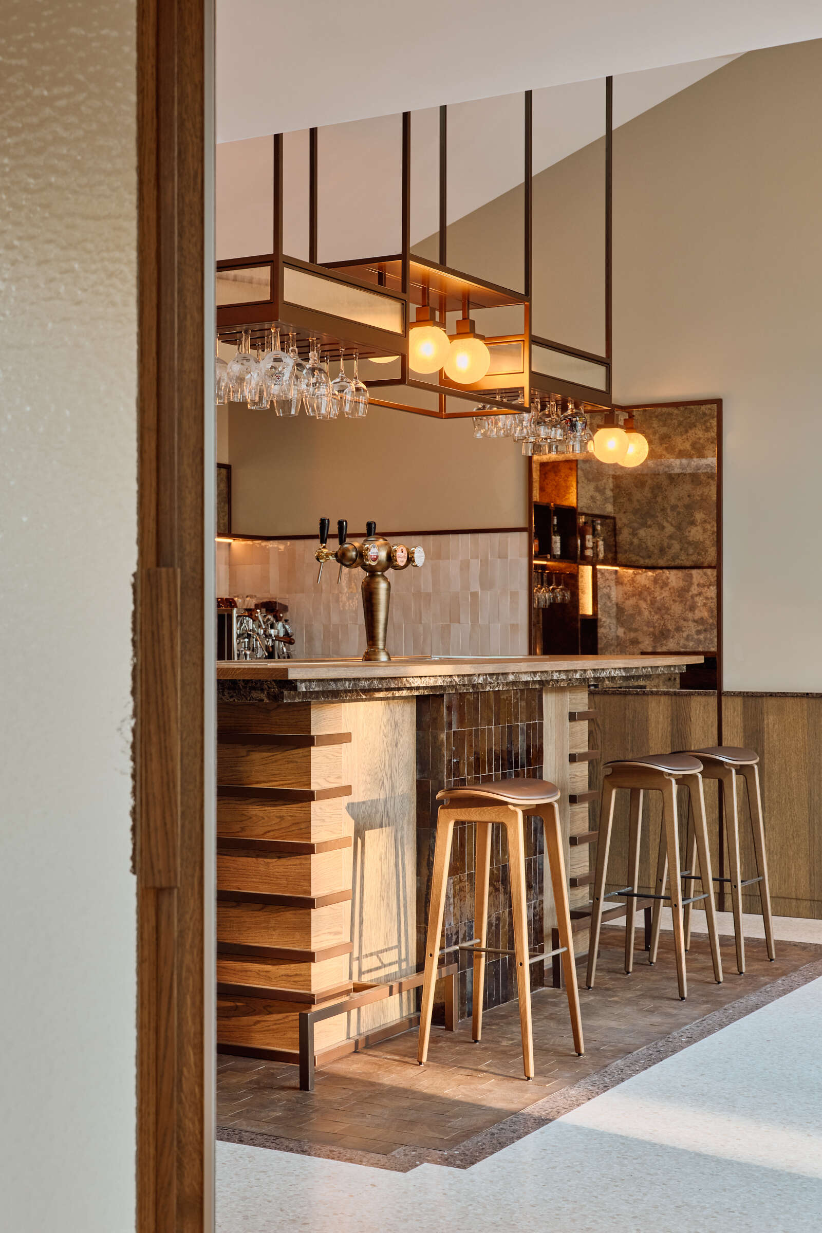 Terrazzo, brass shelving, zellige tiles, and warm brown tones give this private home bar an unforgettable atmosphere.