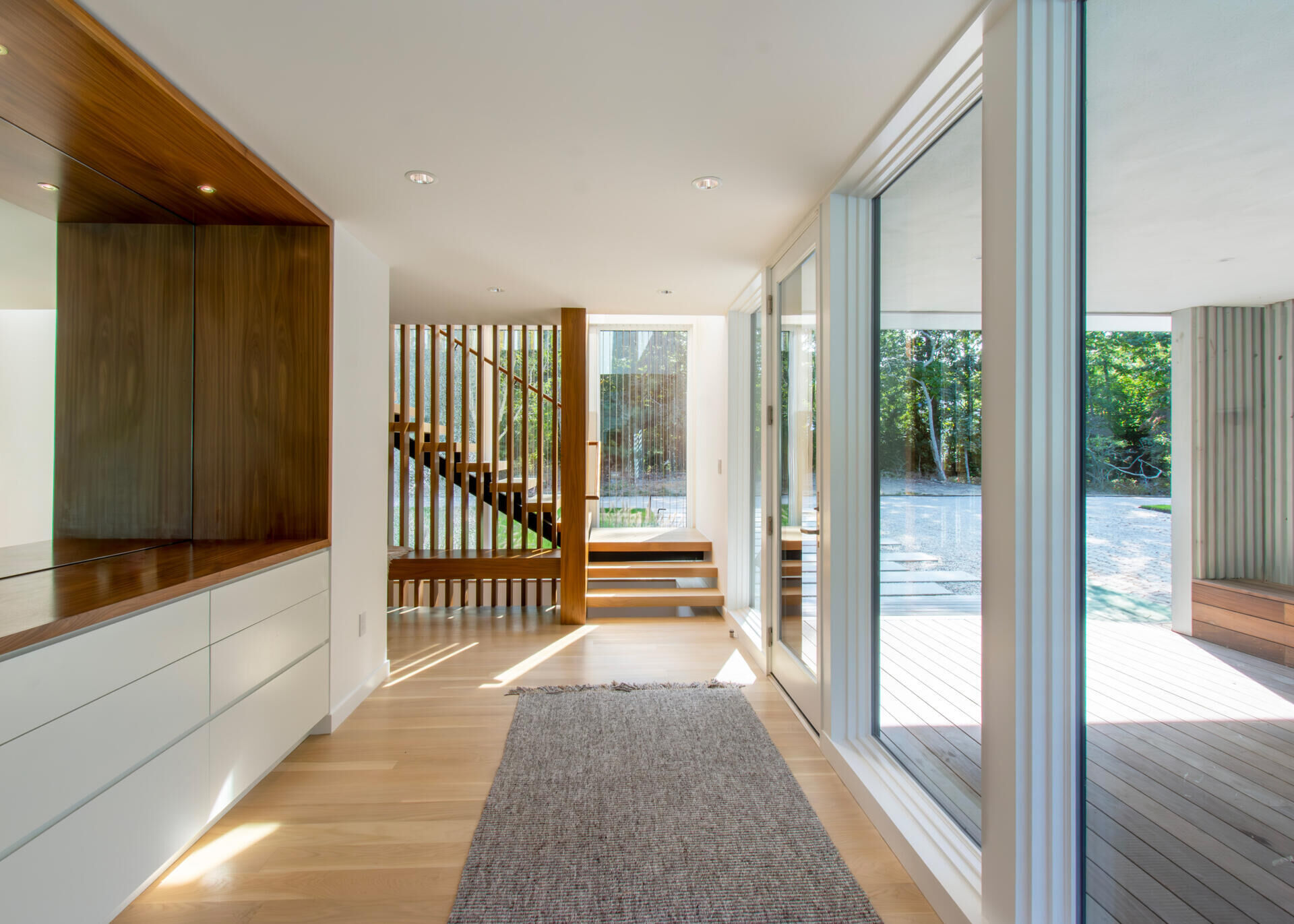 Cedar screens, layered pathways, and low entry ceilings create a dramatic transition into the bright living spaces beyond.