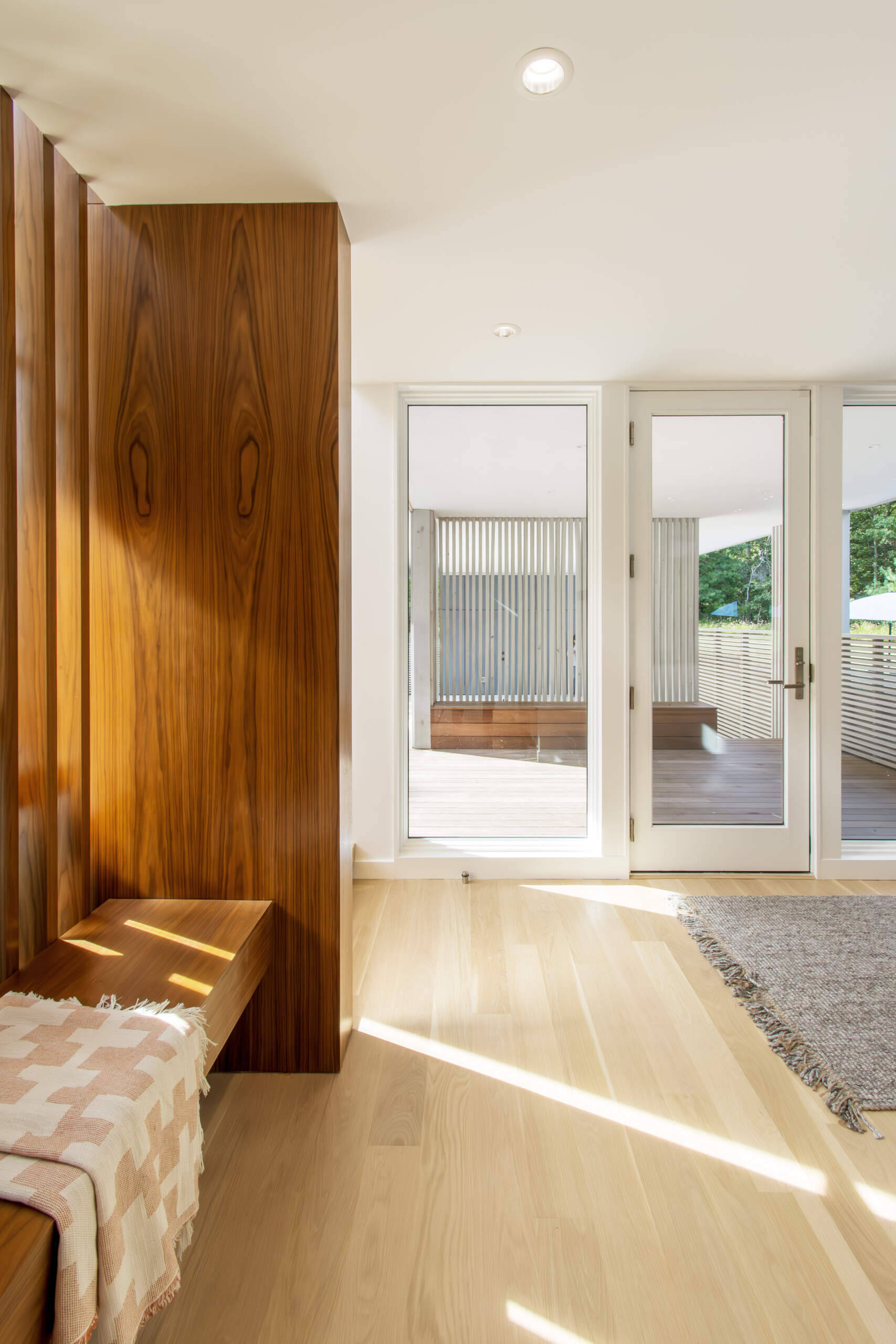 Cedar screens, layered pathways, and low entry ceilings create a dramatic transition into the bright living spaces beyond.
