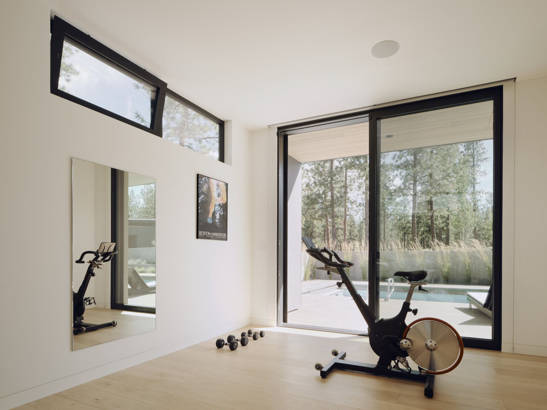 This modern home gym combines minimalist interiors with large forest-facing windows for a bright and energizing workout space.