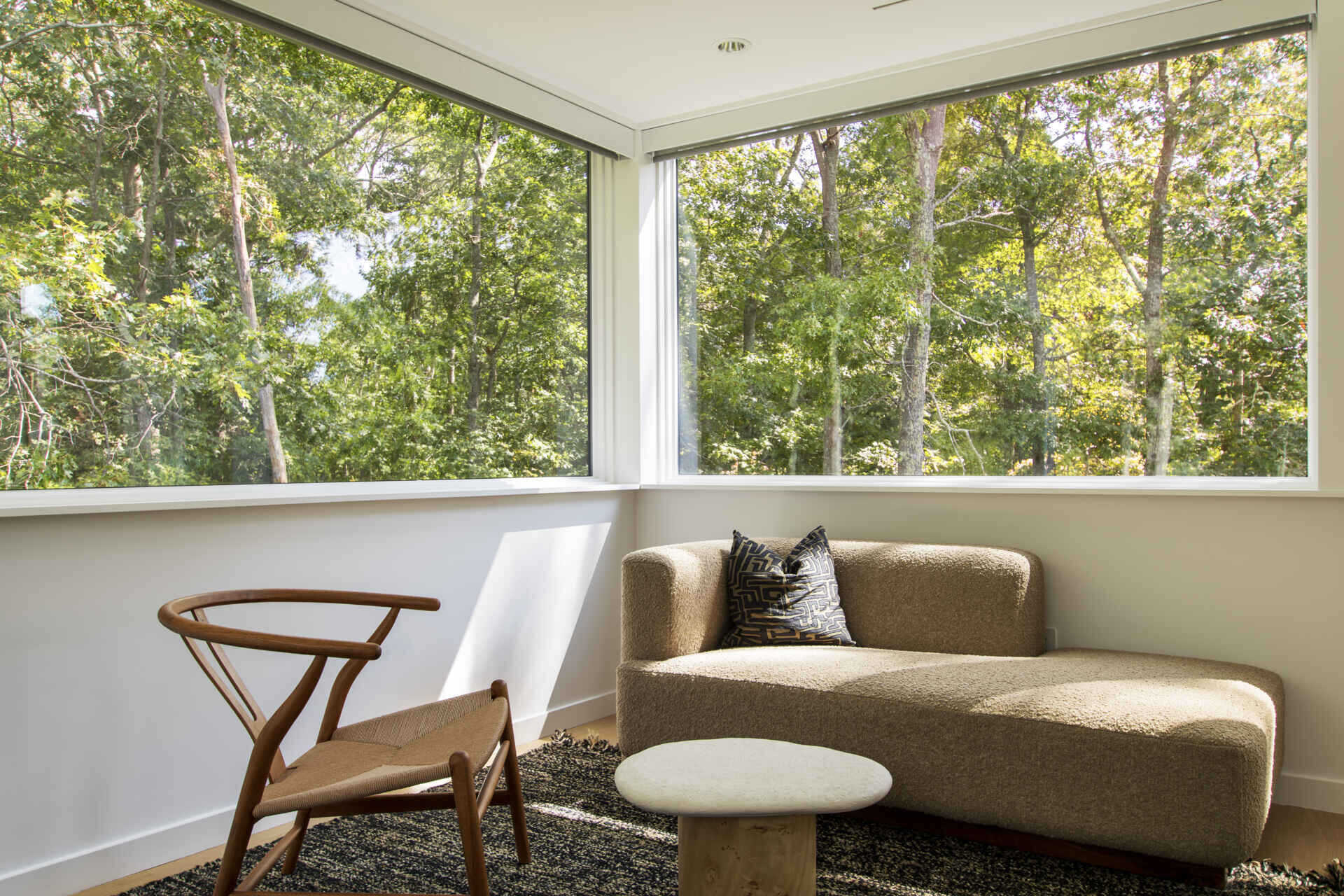 Large windows and minimal interiors create a calm modern workspace surrounded by trees.