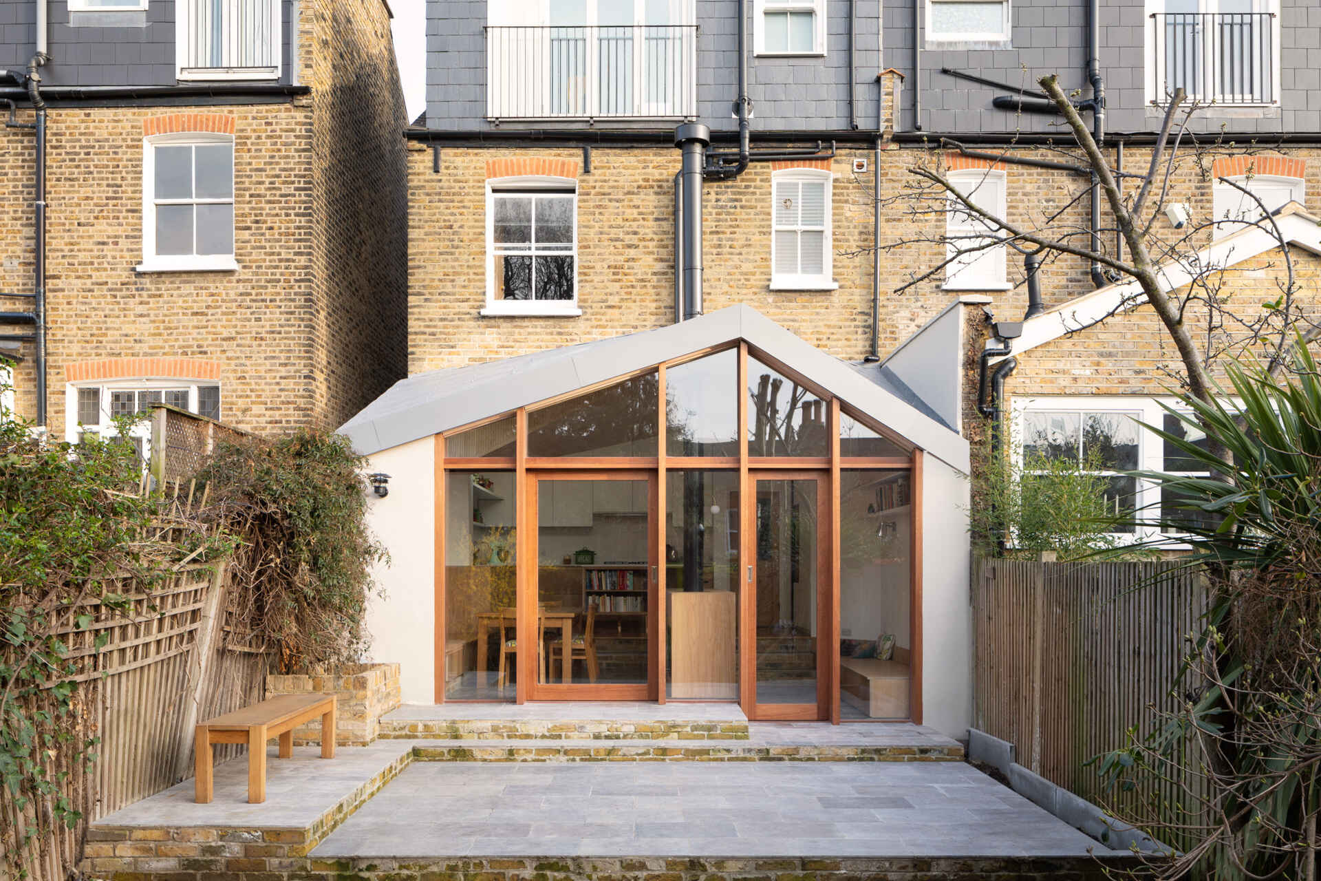 This London extension by Turner Architects uses wood-framed windows and a sculptural roofline to bring more light and garden views into the family home.