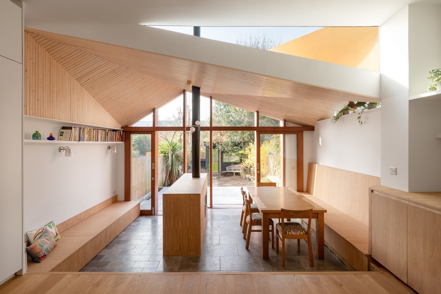 An angled timber ceiling brings warmth, texture, and framed sky views into this contemporary London home extension.