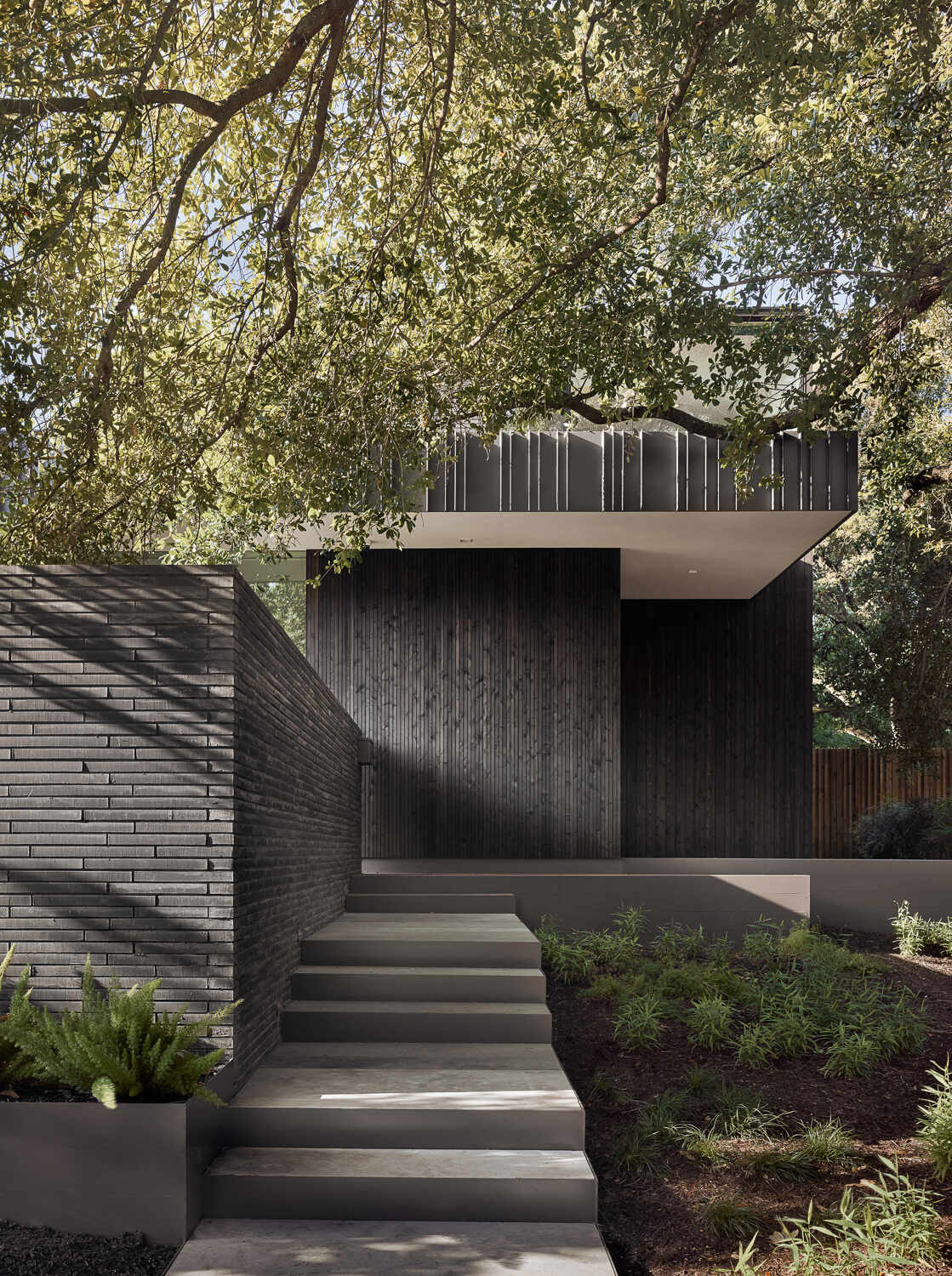 Tour the bold exterior of Tarrytown Residence, where black brick, ebony-stained cedar, custom steel detailing, and expansive glass walls create a contemporary architectural statement in Austin, Texas.