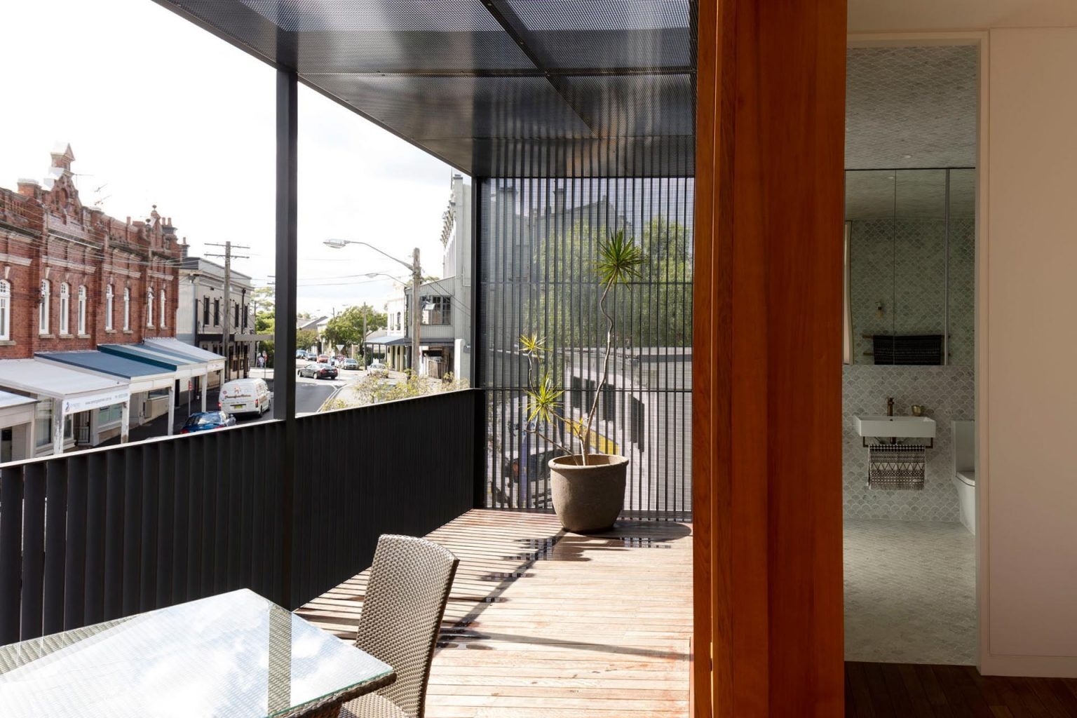 A front-facing balcony extends the living space outward, offering an elevated view over the surrounding Sydney streetscape and neighbouring urban fabric.