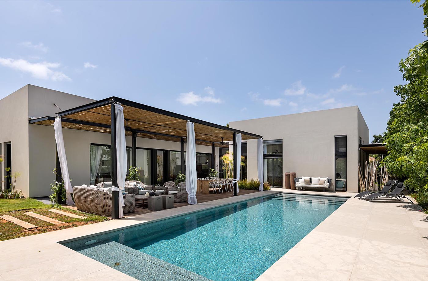This modern home by Neuman Hayner Architects combines bamboo pergolas, minimalist interiors, and multiple outdoor entertaining spaces connected through shaded pathways.