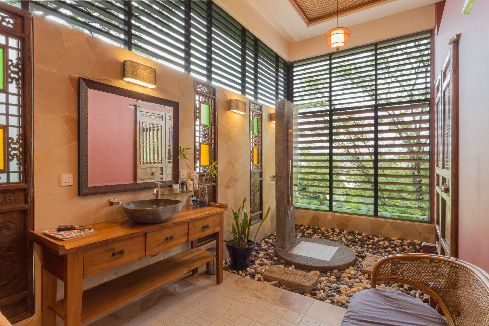 In the bathroom, the look is more natural aesthetic, with stones surrounding the base of the shower, and screens allowing the scenery to be enjoyed.