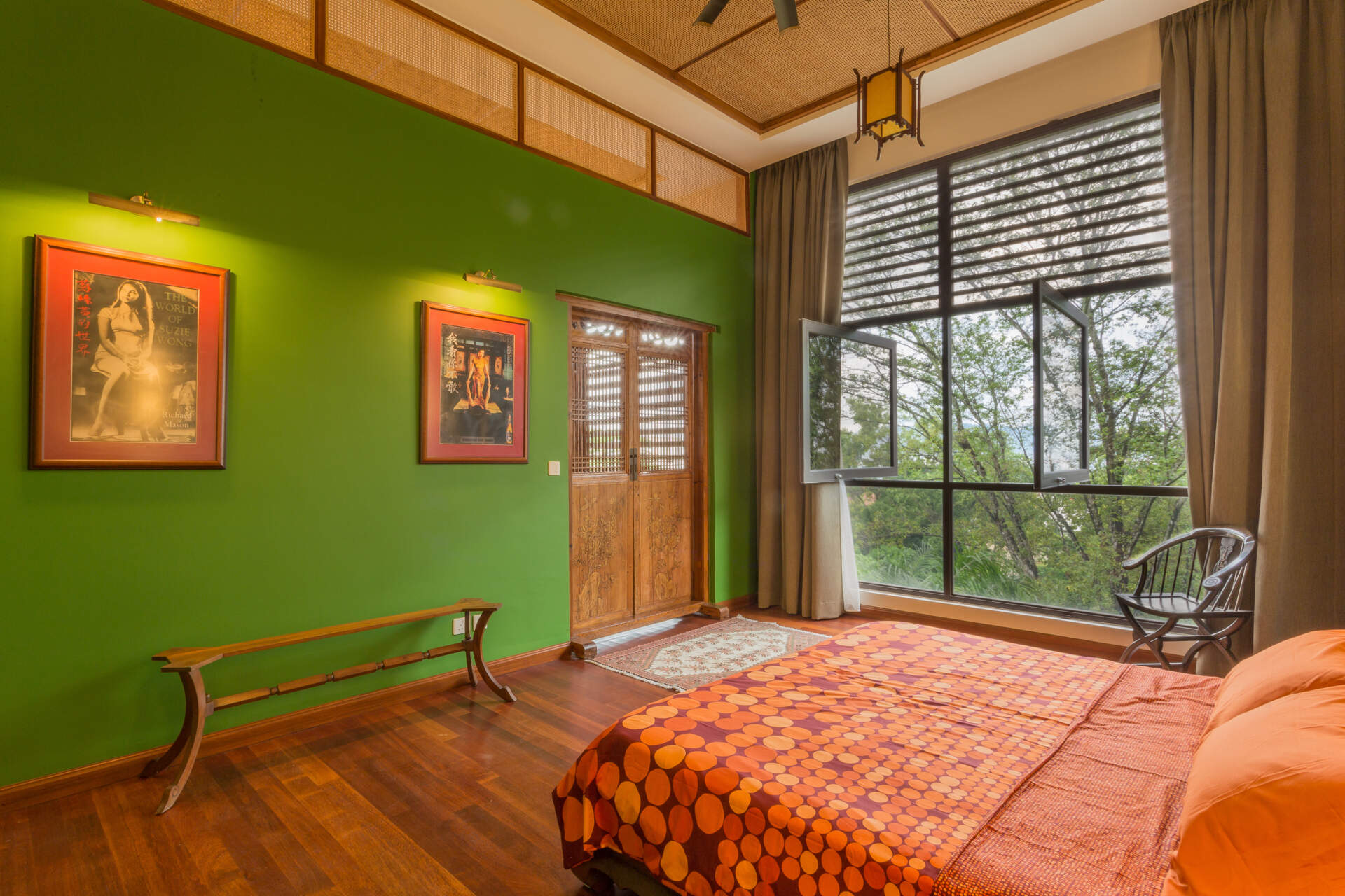 A modern bedroom in a tropical home draws inspiration from outside with the use of wood and a bright green accent wall.