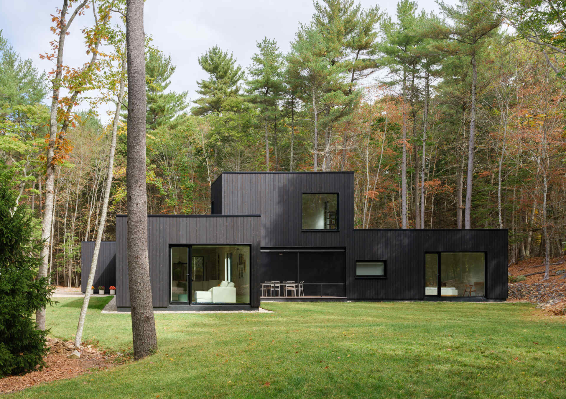 This Maine home uses black charred wood siding and dramatic floor-to-ceiling glass to create a modern exterior in the forest.