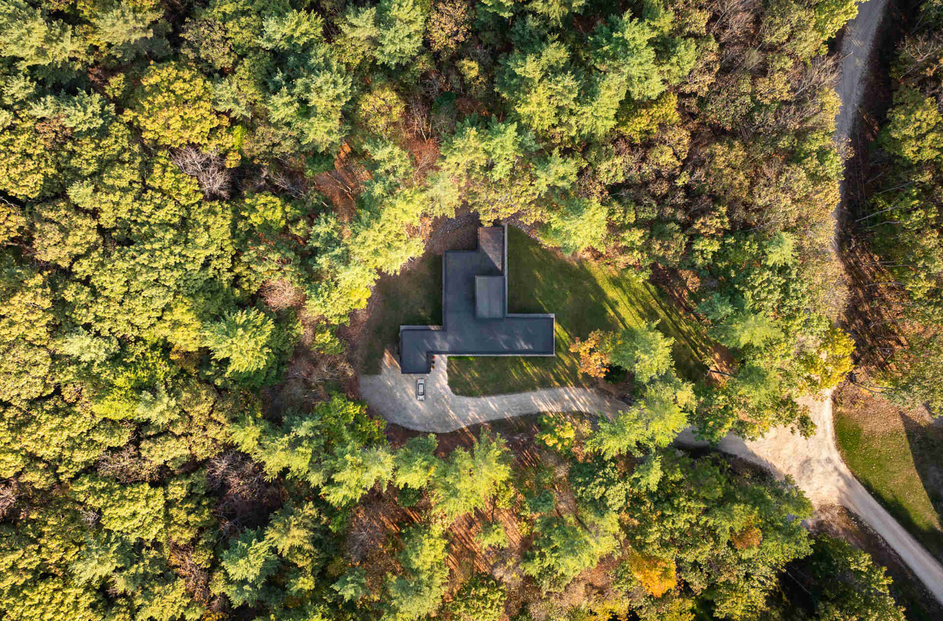 This Maine home uses black charred wood siding and dramatic floor-to-ceiling glass to create a modern exterior in the forest.