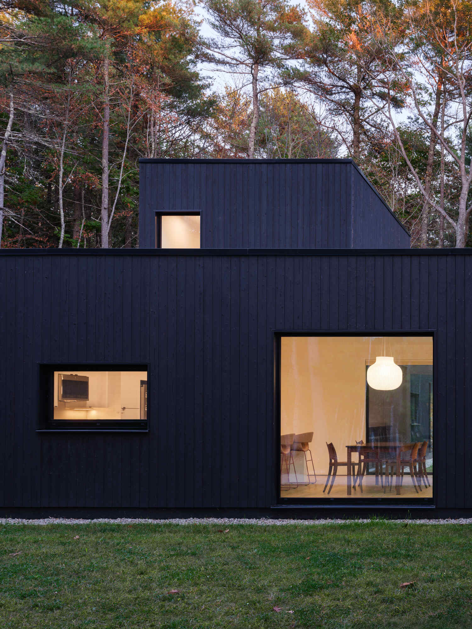 This Maine home uses black charred wood siding and dramatic floor-to-ceiling glass to create a modern exterior in the forest.