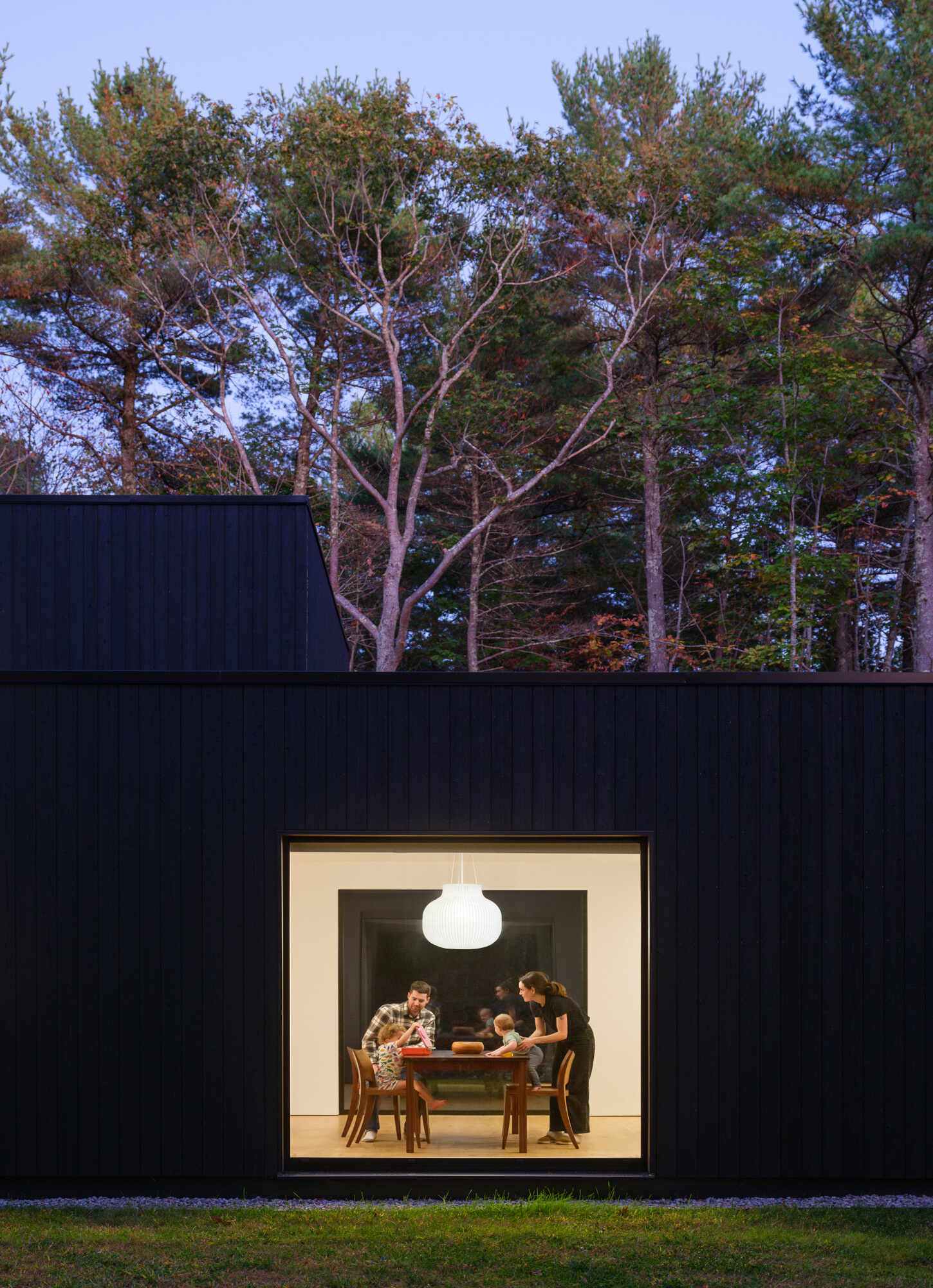 This Maine home uses black charred wood siding and dramatic floor-to-ceiling glass to create a modern exterior in the forest.