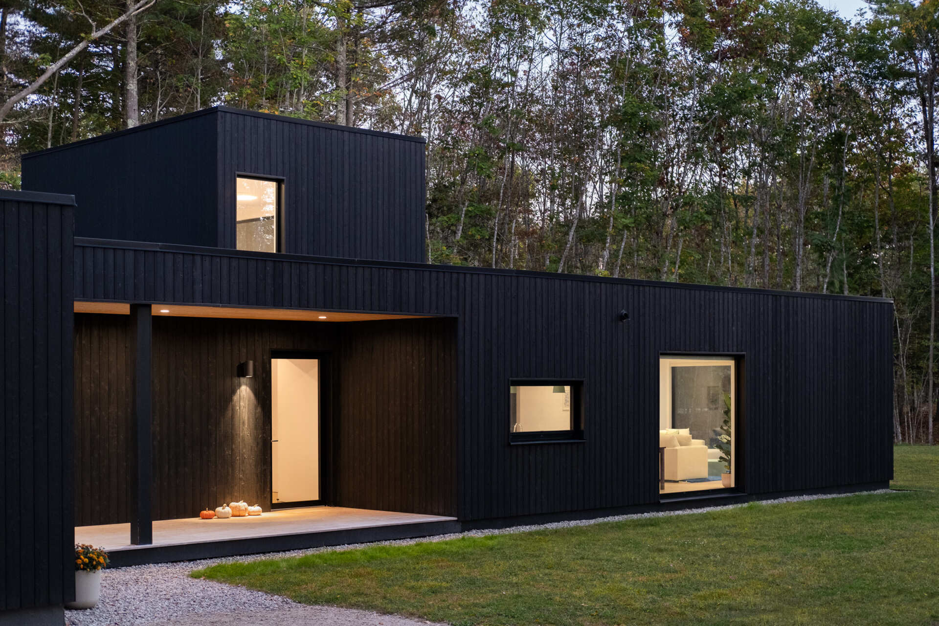 This Maine home uses black charred wood siding and dramatic floor-to-ceiling glass to create a modern exterior in the forest.