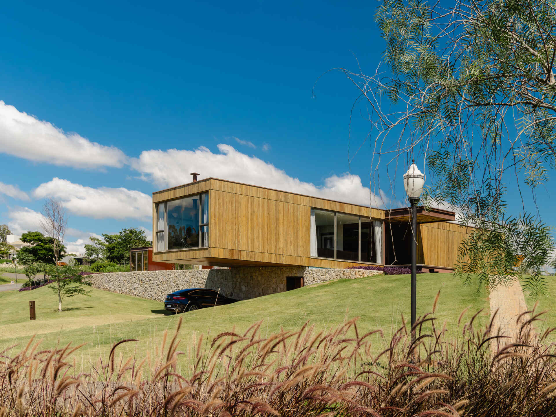 Casa Themis features a dramatic cantilevered living room suspended above a stone base, while integrated solar panels add sustainable performance to the sleek modern design.